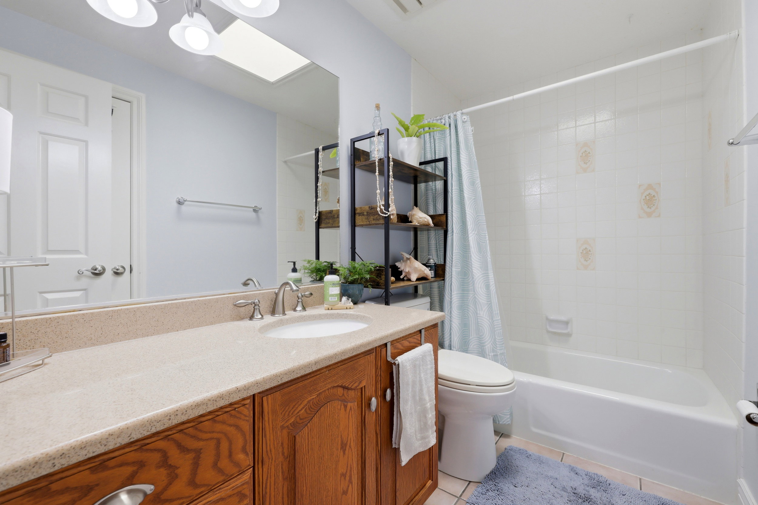 Bathroom featuring a single vanity with a light-toned countertop, an integrated sink, and wood-finish cabinetry