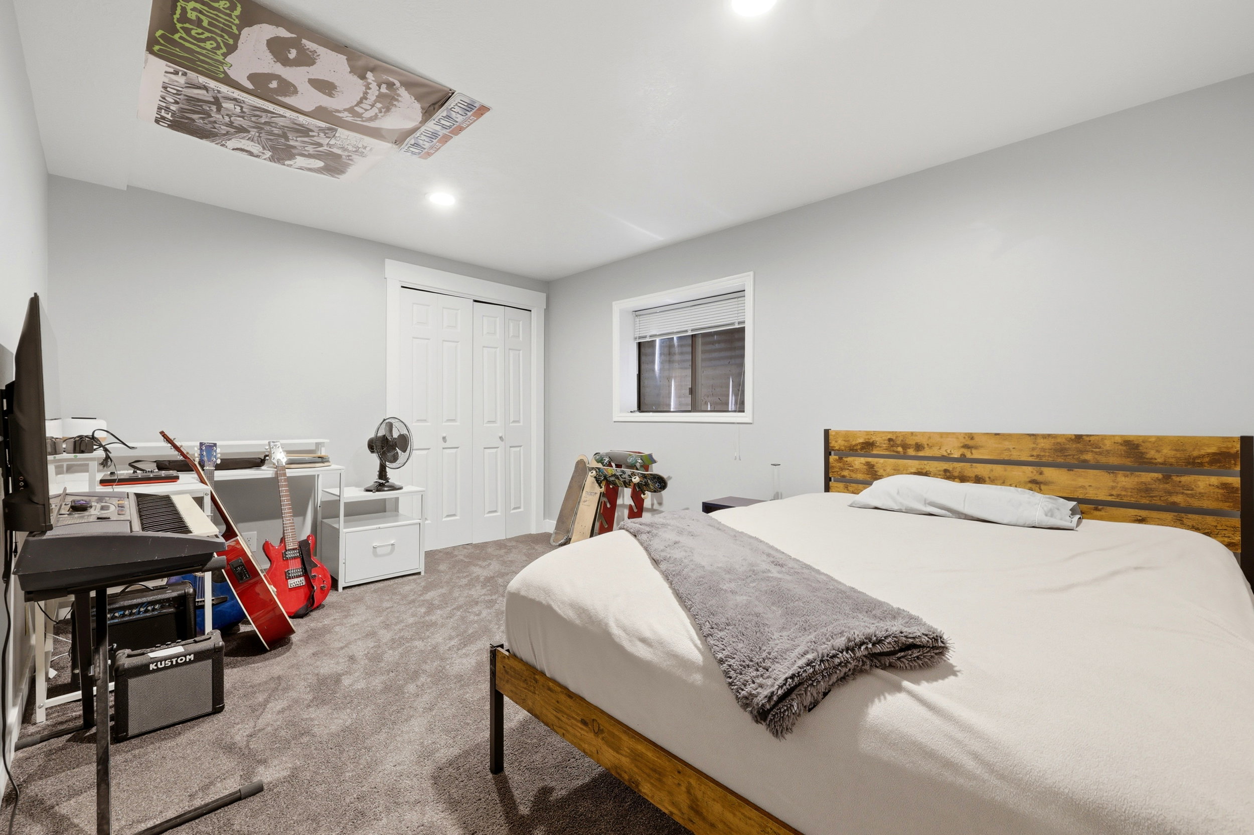 Bedroom featuring light gray wall paint, gray carpet, a white framed window with blinds, and a double-door closet