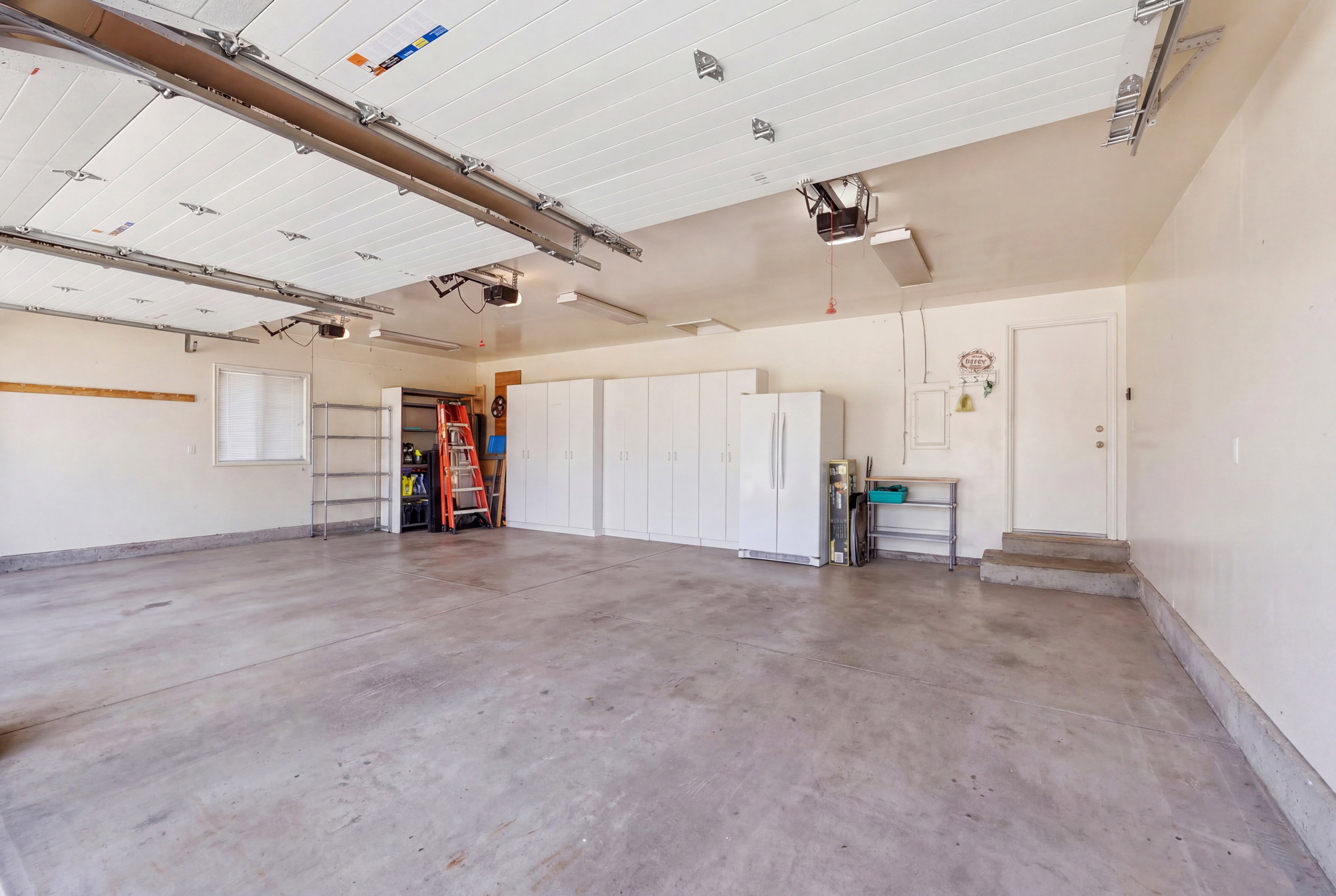 Spacious 3 car garage with concrete flooring, and overhead lighting.
