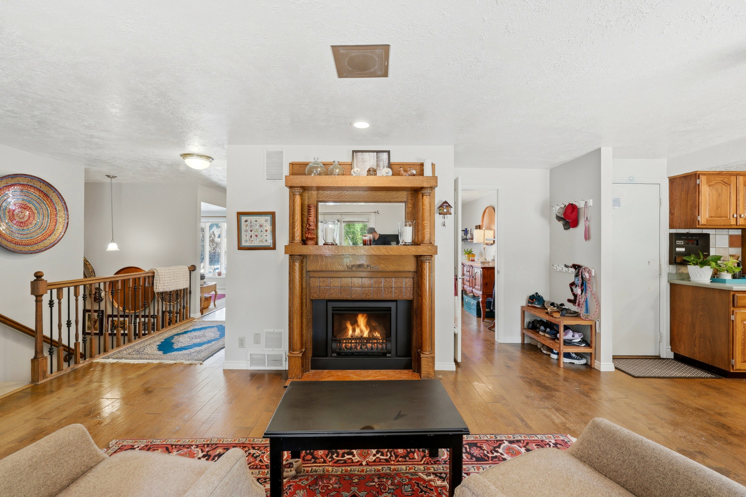 Living area featuring a prominent wood fireplace with an ornate mantel and integrated mirror, hardwood flooring, and light-toned walls