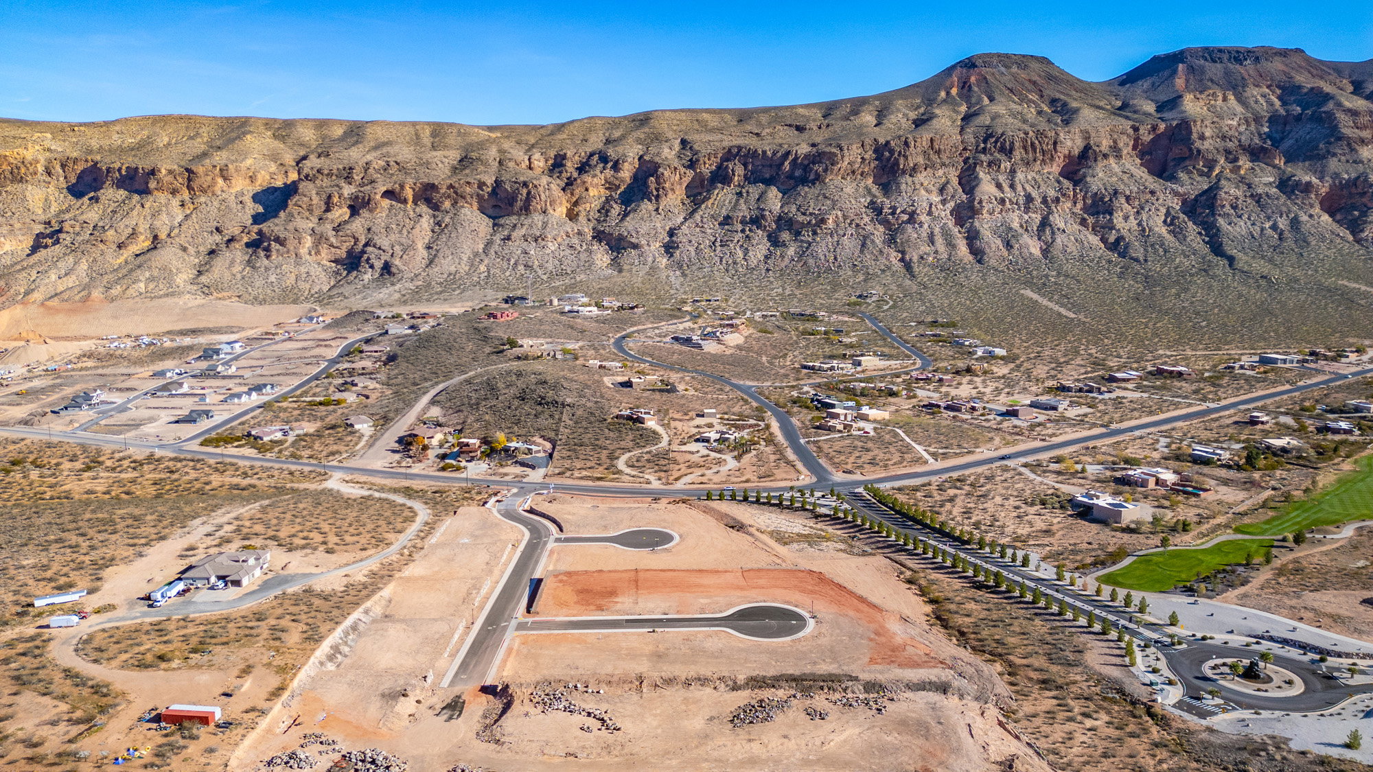 Expansive desert landscape featuring mountain formations and a residential development
