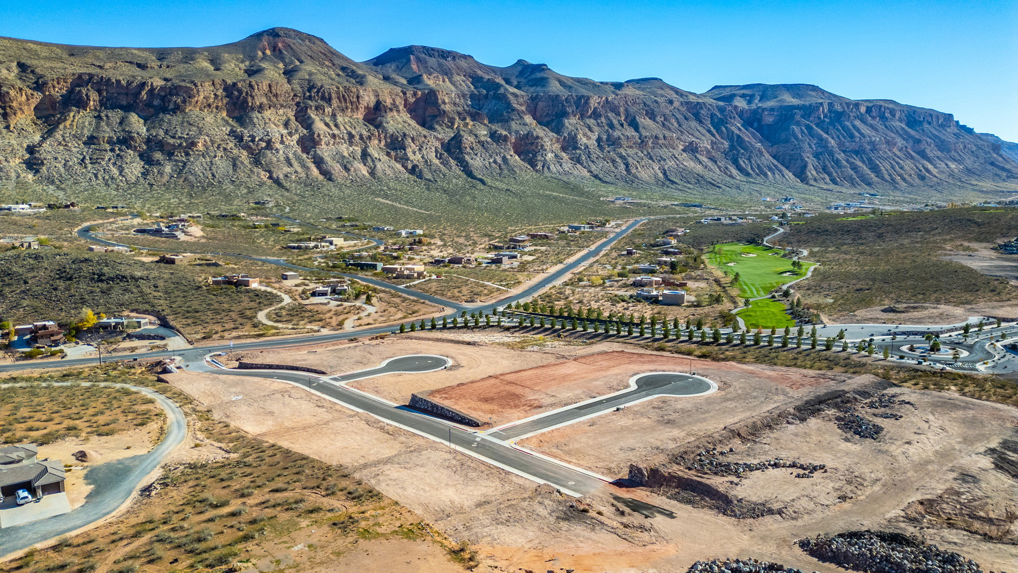 Expansive land parcels with new road infrastructure, surrounded by natural desert landscaping and dramatic mountain ranges