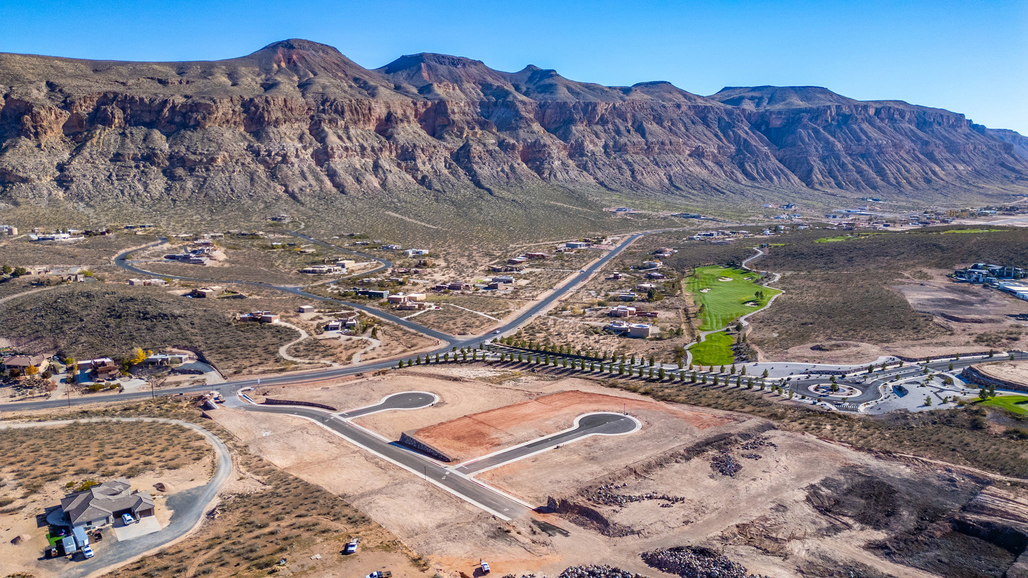 Expansive desert landscape featuring rugged mountain terrain, a paved road network, and multiple residential properties