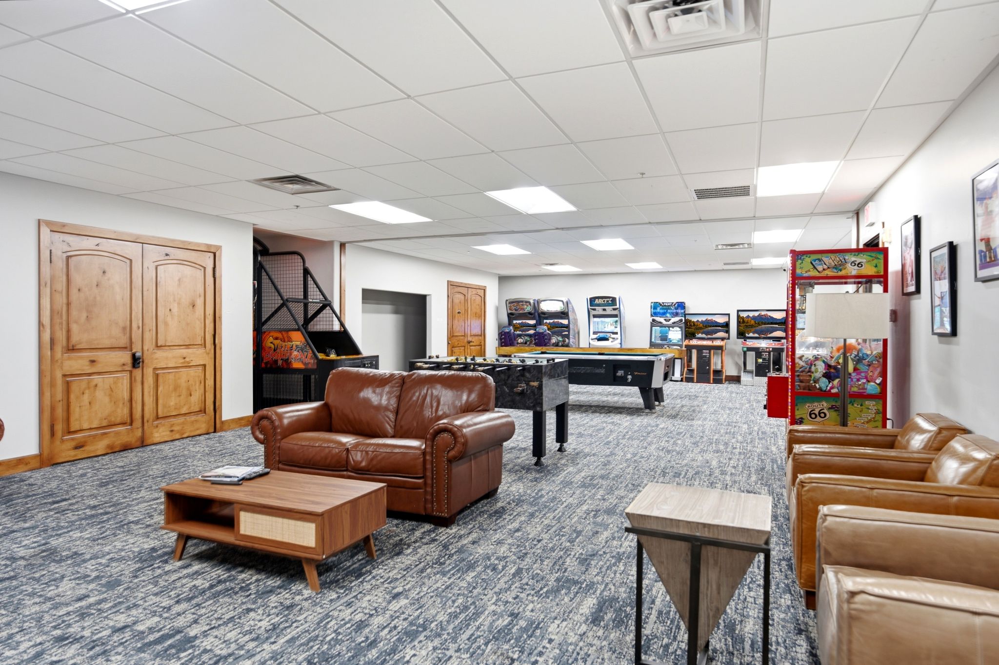Spacious recreation area featuring wood-finish double doors and an expansive patterned carpet