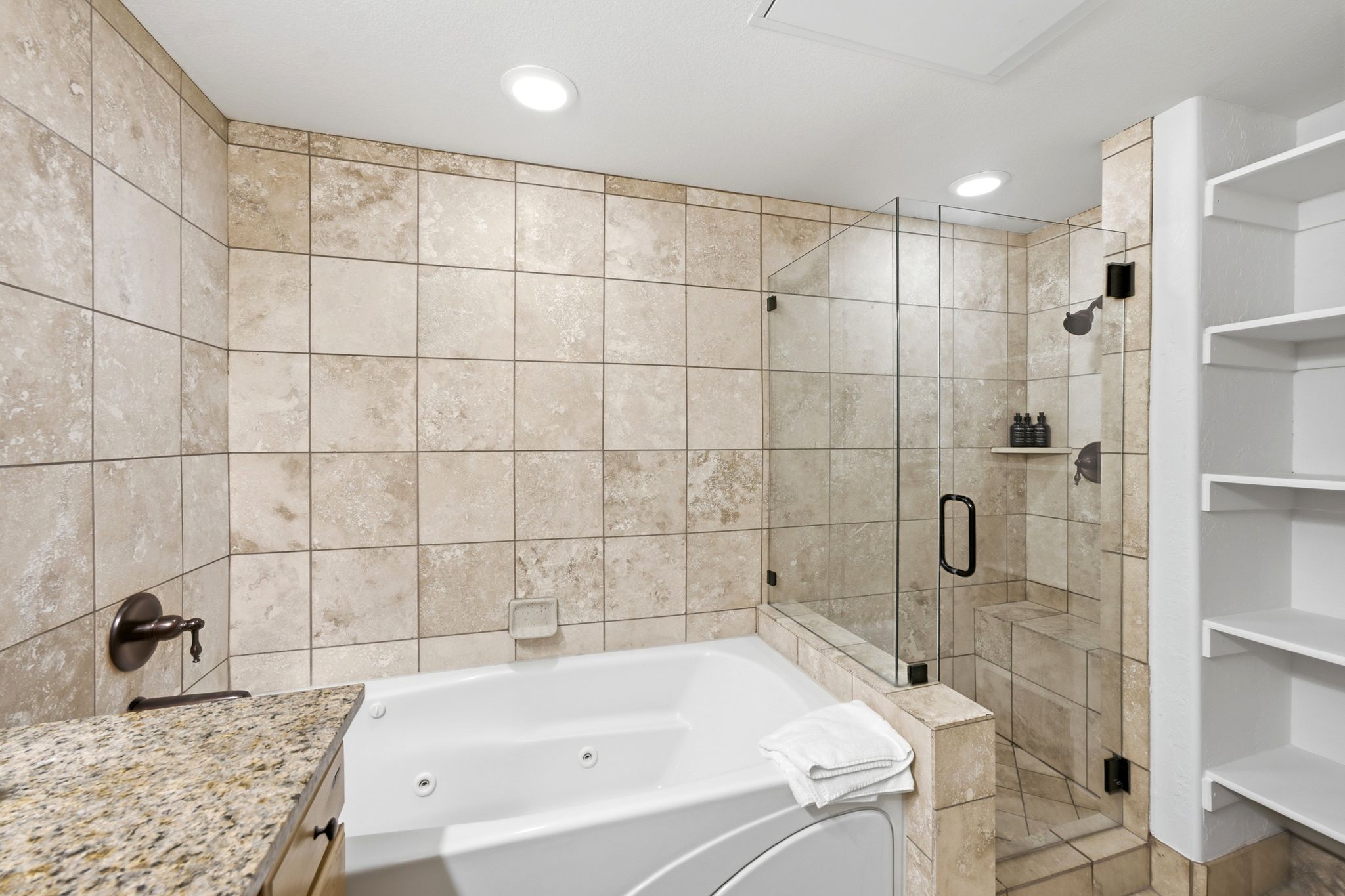 Jetted soaking tub with surrounding stone-finish tile