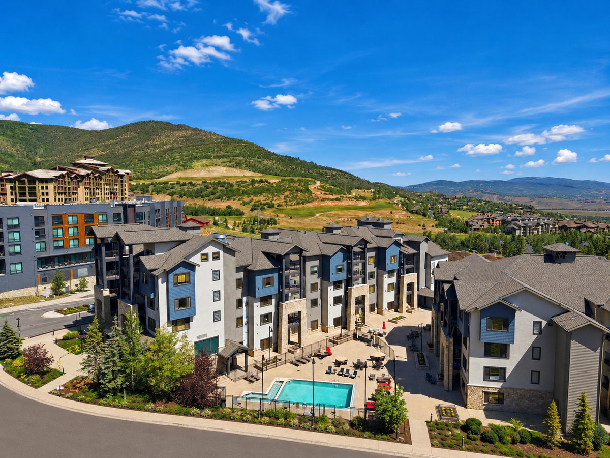 Modern multi-story buildings featuring varied facades, a fenced outdoor swimming pool, and dedicated lounge areas with seating