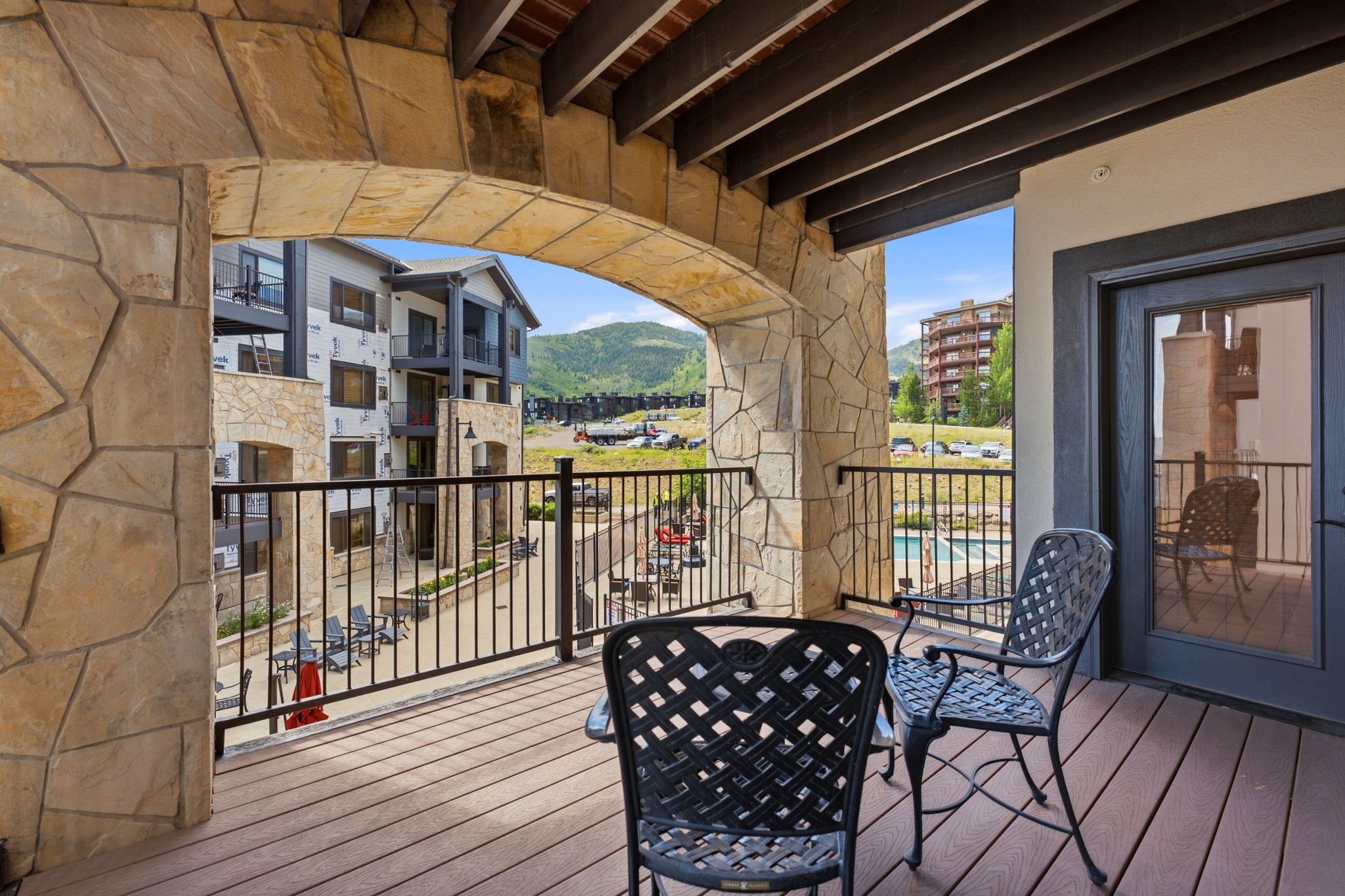 Expansive balcony featuring composite decking, a stone archway, and wood beam ceiling