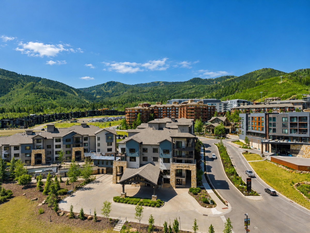 Modern alpine-style condominium complex featuring multi-story buildings with varied facades, covered entryways, and private balconies