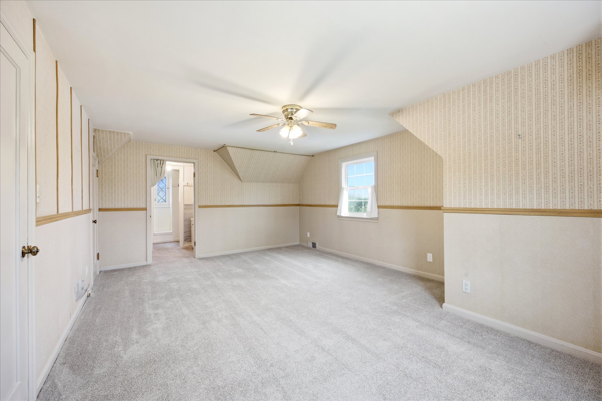 Spacious room featuring light-colored carpeting and a ceiling fan with integrated lighting