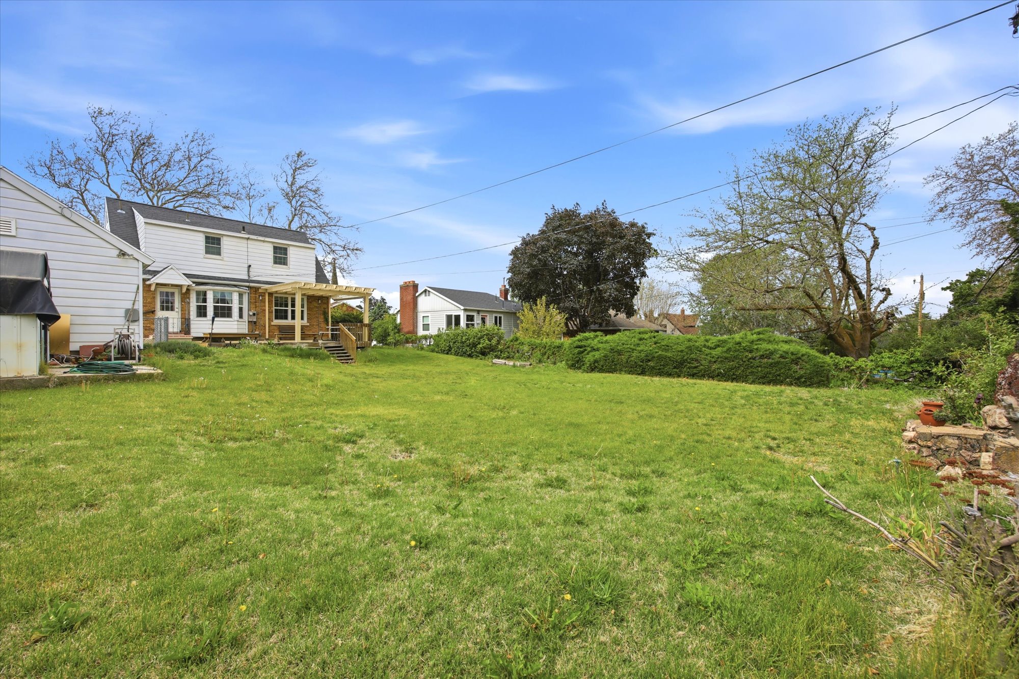 Expansive lawn area with a two-story residence featuring white siding and a rear addition with multiple windows