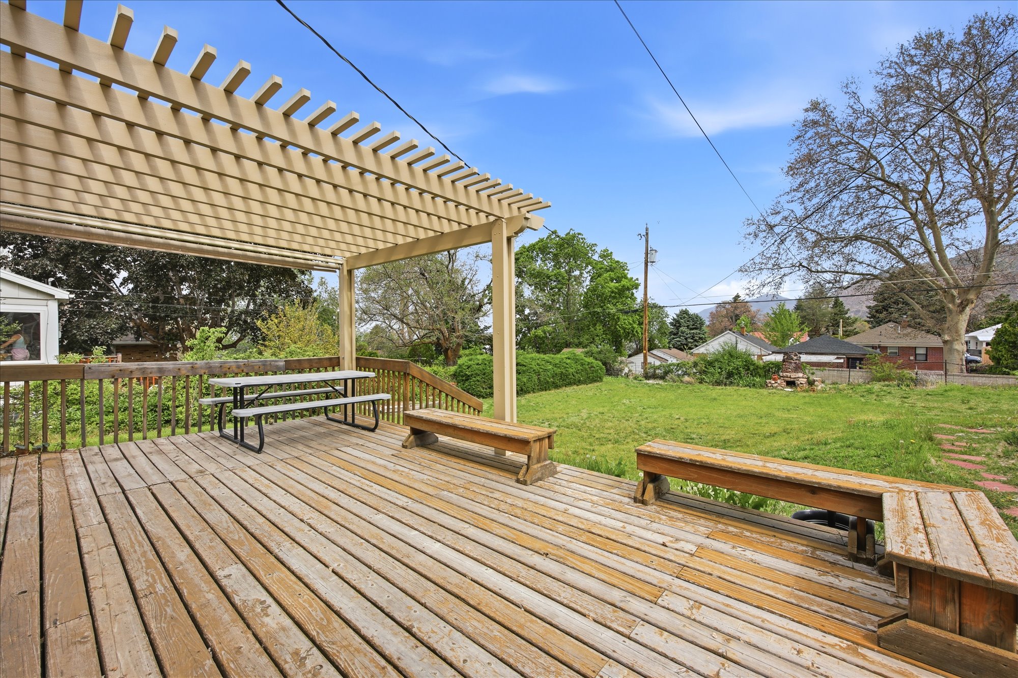 Expansive wooden deck with a slatted pergola overhead