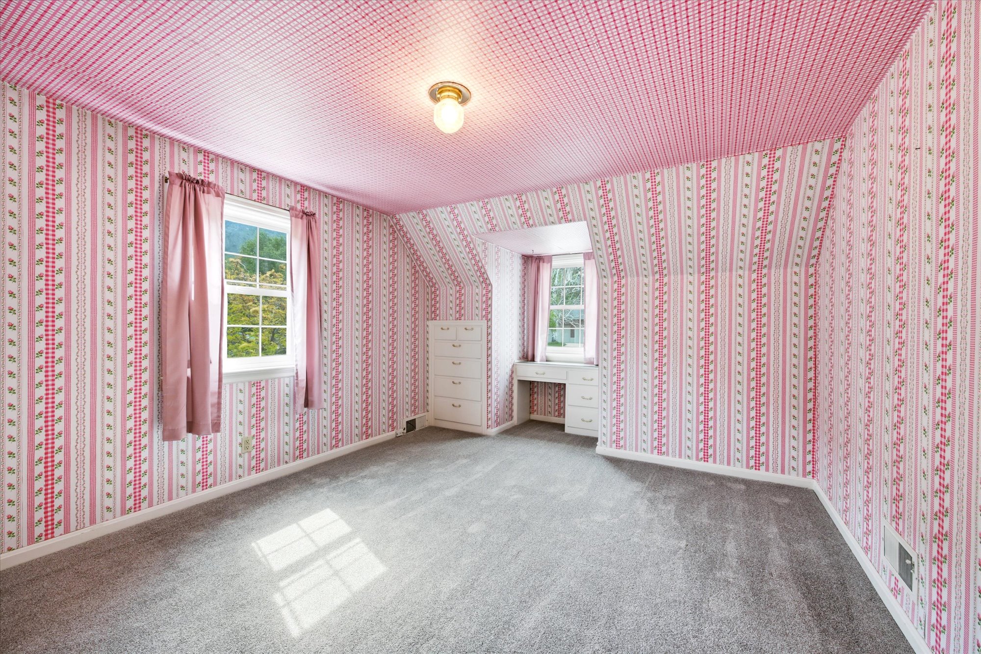Interior room featuring patterned wallpaper, grey carpet flooring, and a built-in vanity with drawers