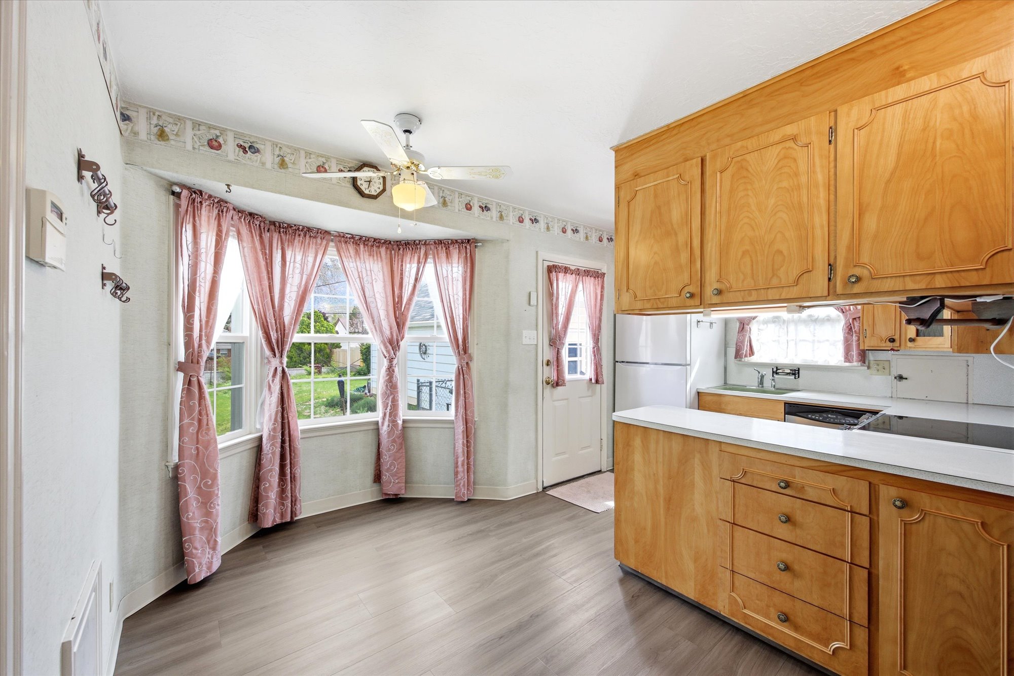 Kitchen featuring wood cabinetry, white countertops, stainless steel sink, and wood-finish flooring