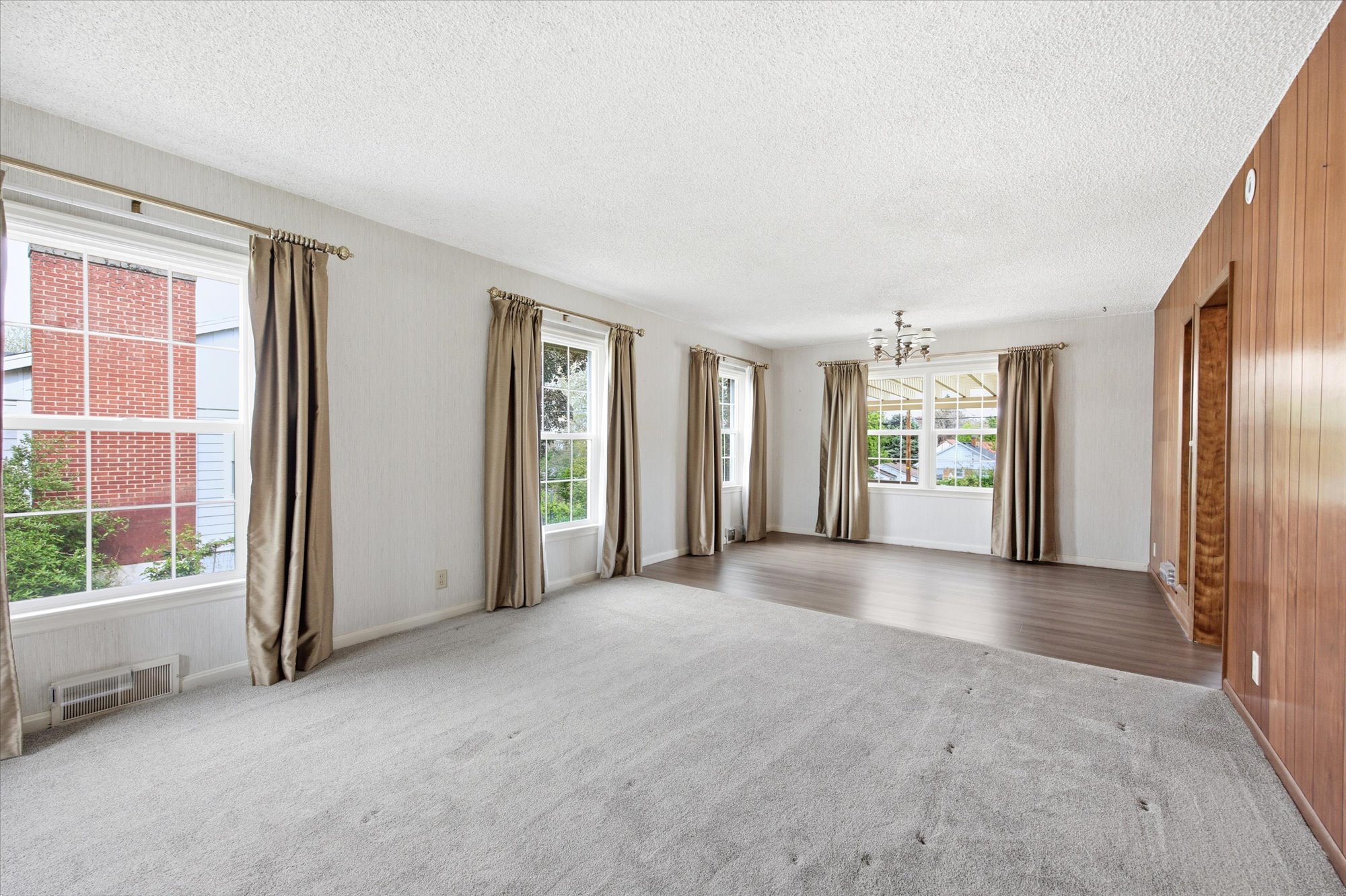 Spacious room featuring light gray carpeting and wood-finish flooring