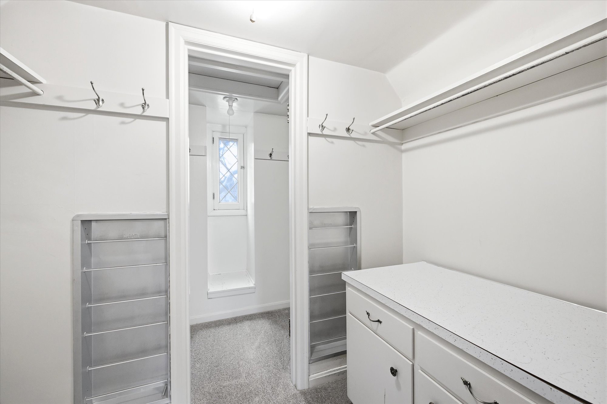 Walk-in closet featuring white built-in cabinetry, overhead shelving, hanging rods, and integrated shoe racks