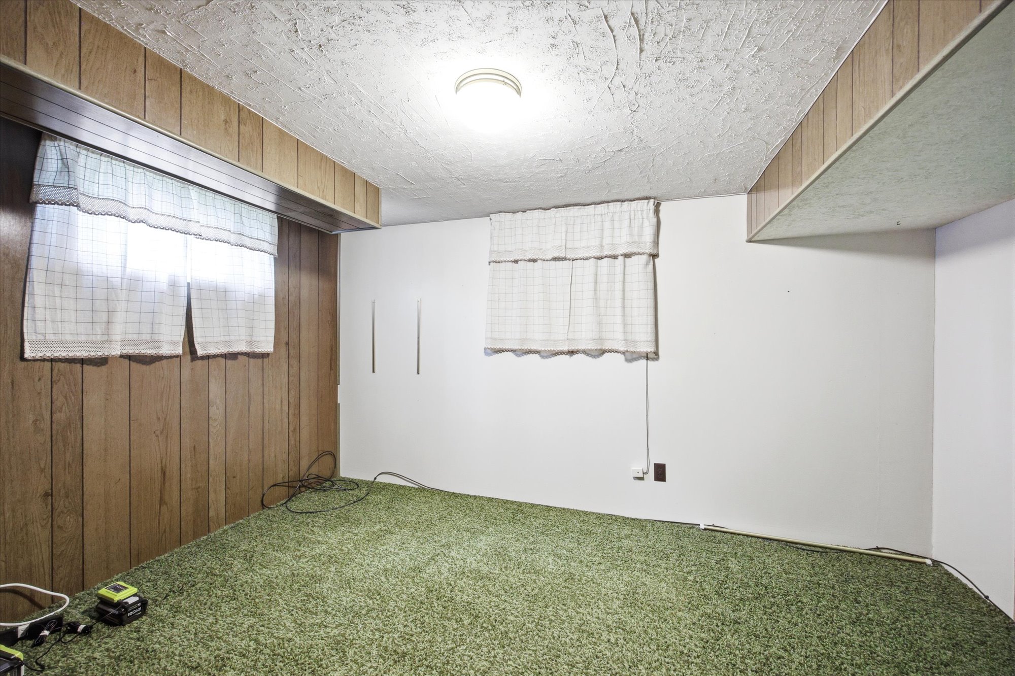Room featuring a textured ceiling, a flush-mount ceiling light, and wall paneling