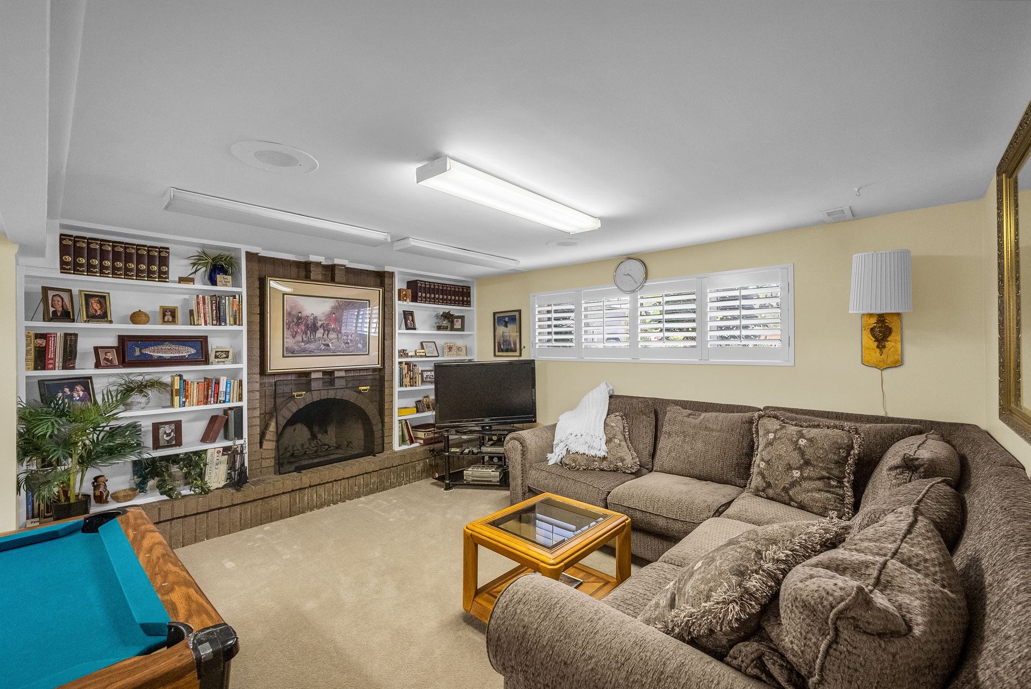 Spacious recreation room featuring a brick wood burning fireplace with a hearth