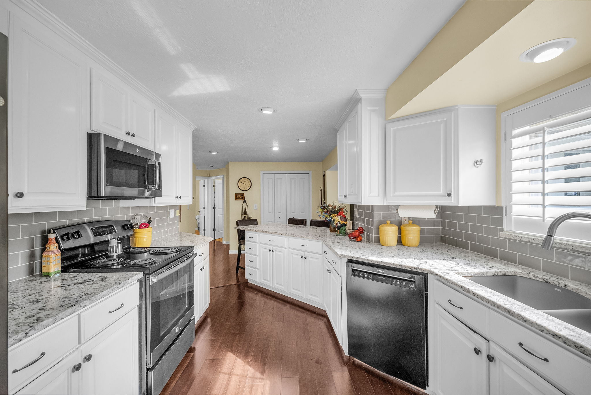 Enjoy this contemporary white kitchen with black and stainless appliances