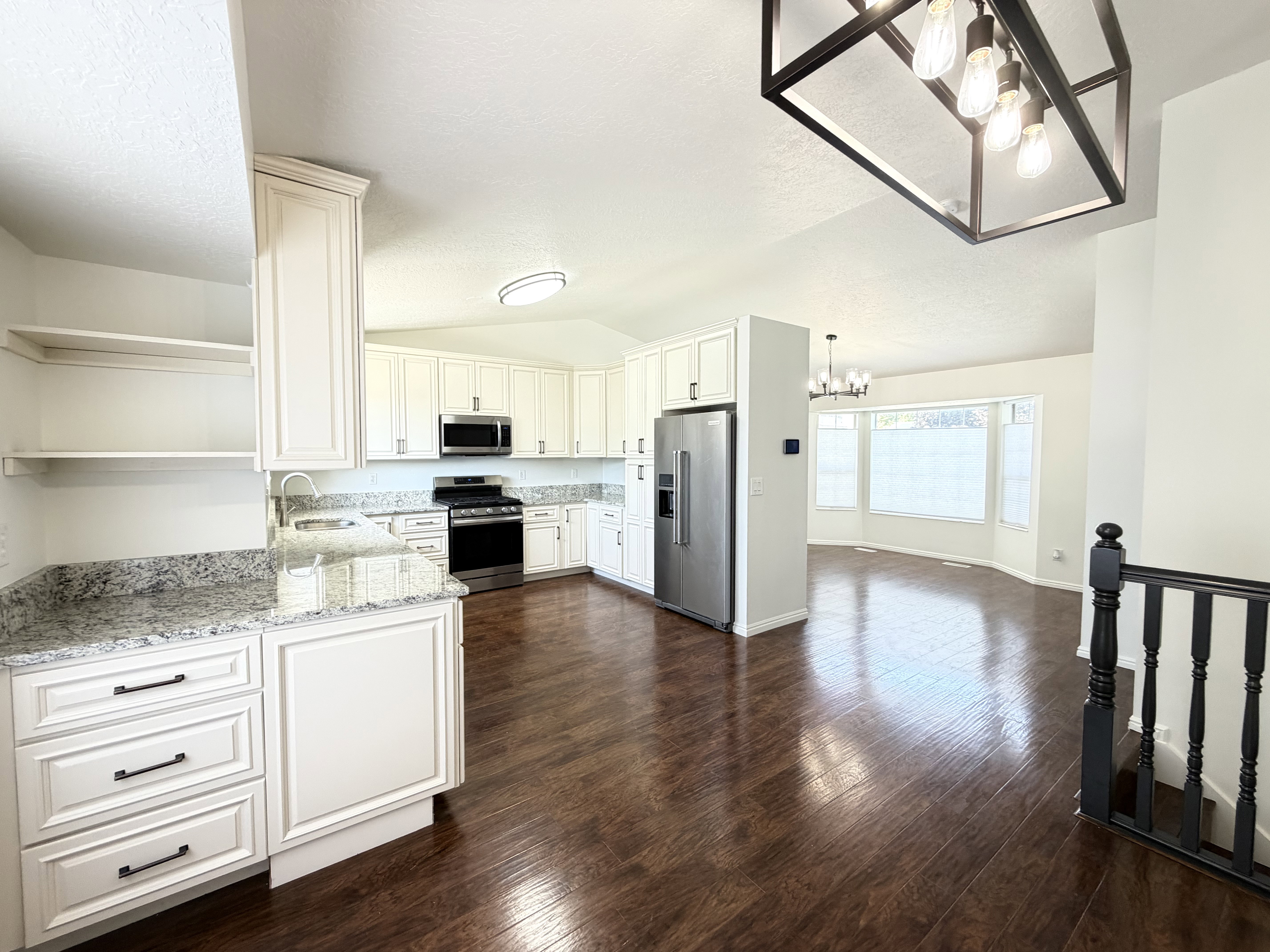 Spacious kitchen featuring white cabinetry, stainless steel appliances, and granite countertops