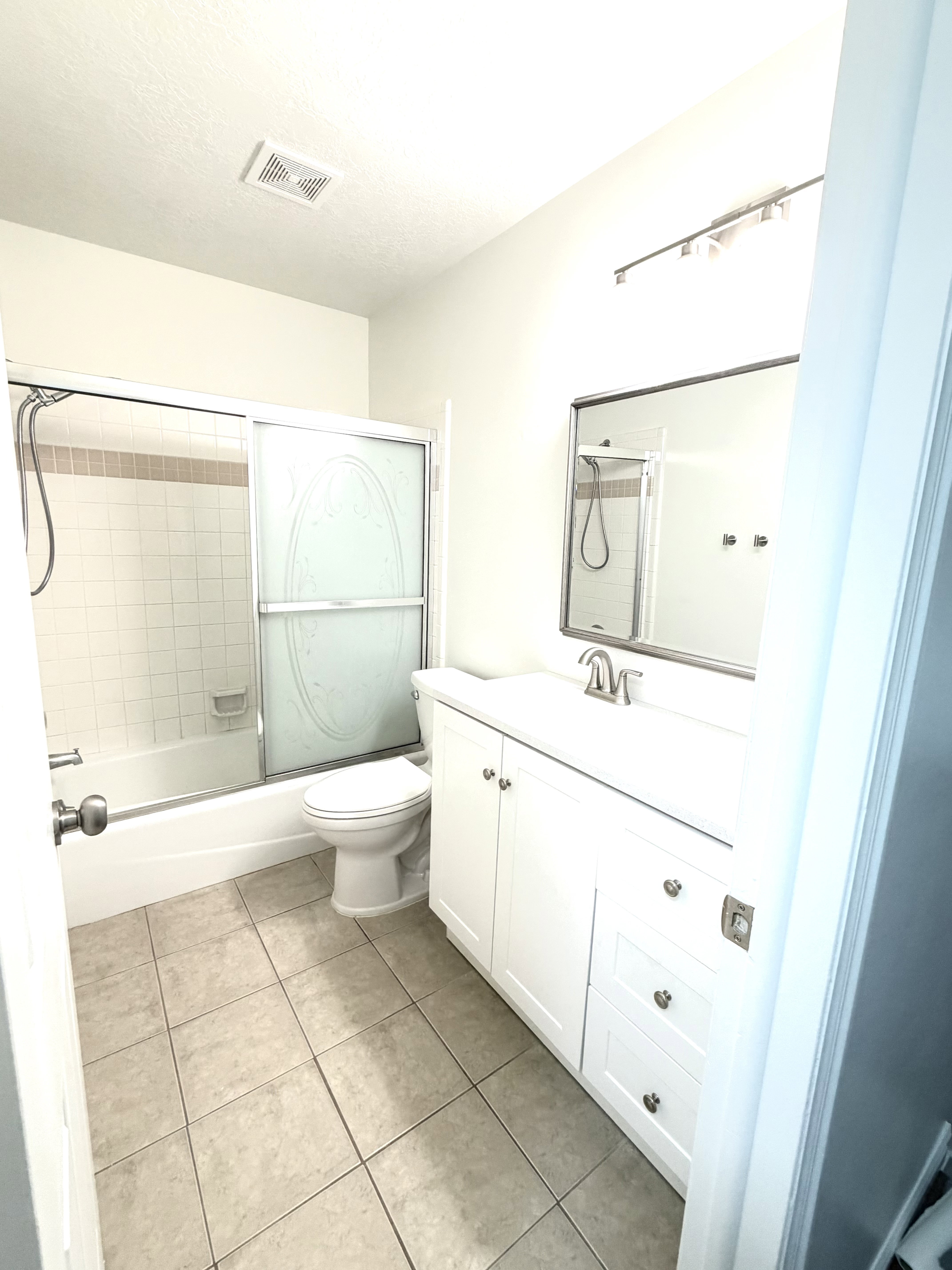 Bathroom featuring a white vanity with integrated sink, rectangular mirror, and silver-tone hardware
