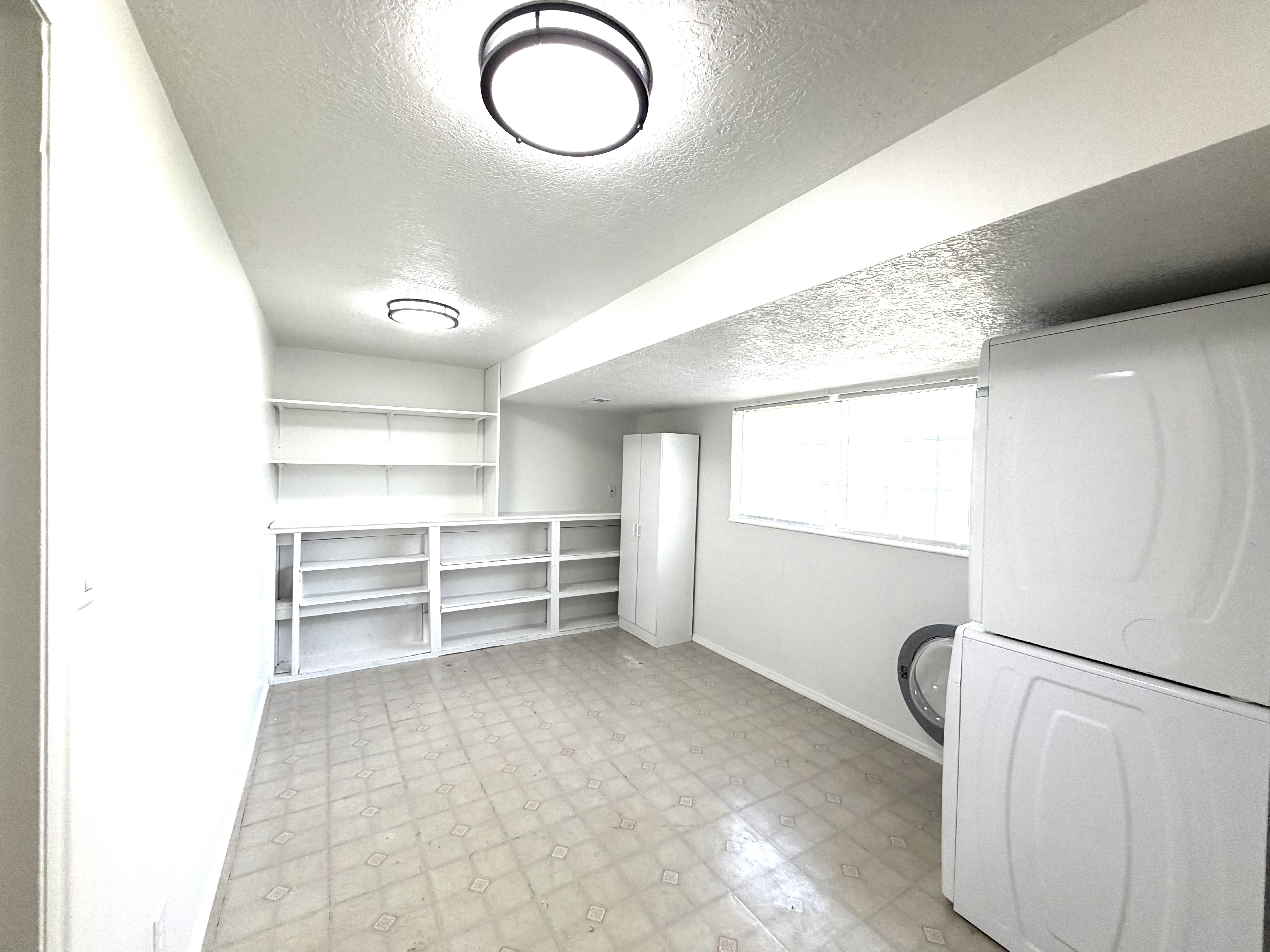 Utility area featuring extensive built-in shelving, a wall-mounted storage cabinet, and window with blinds