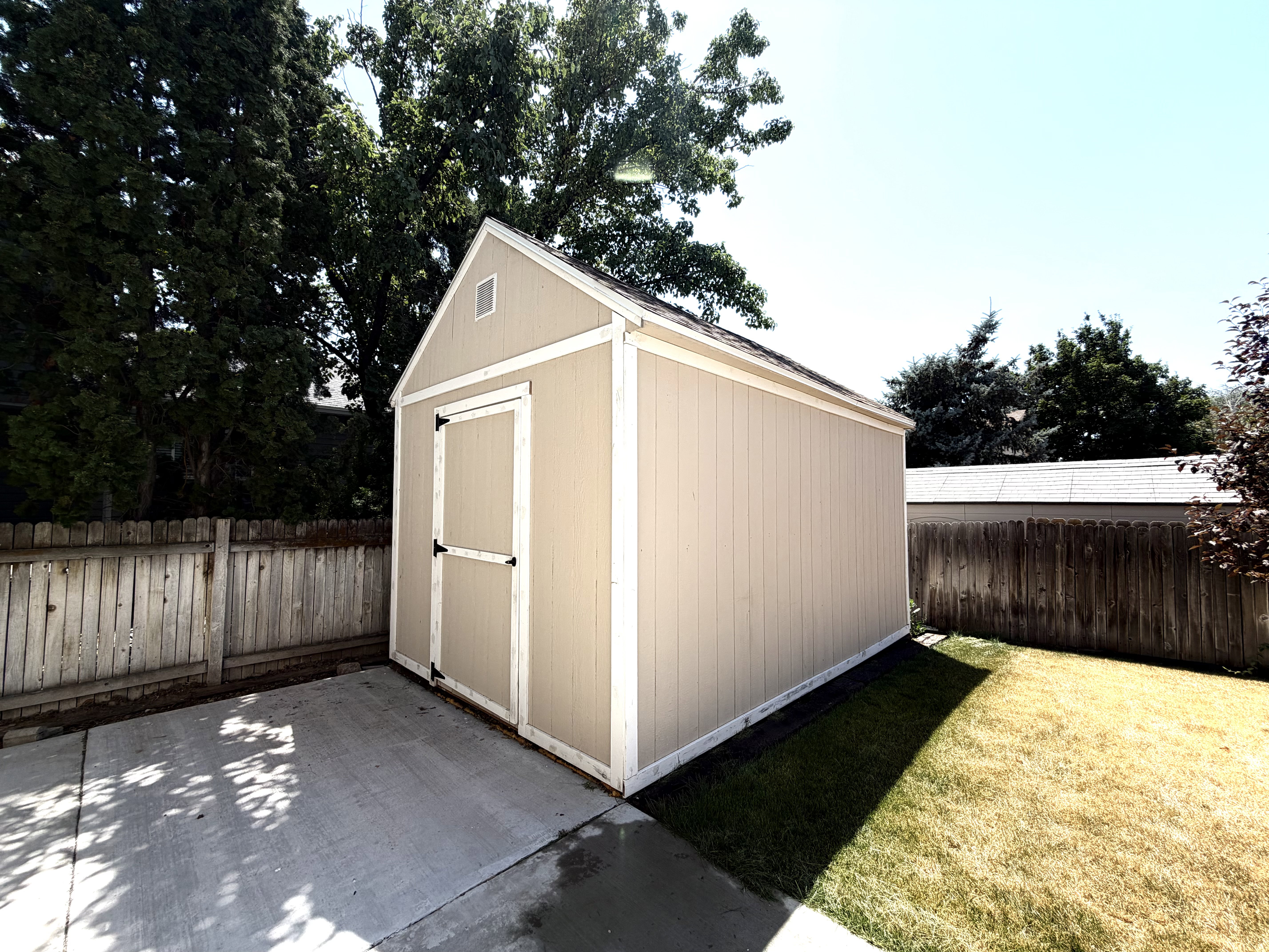 Freestanding storage shed featuring a neutral siding finish, white trim, and an A-frame roof