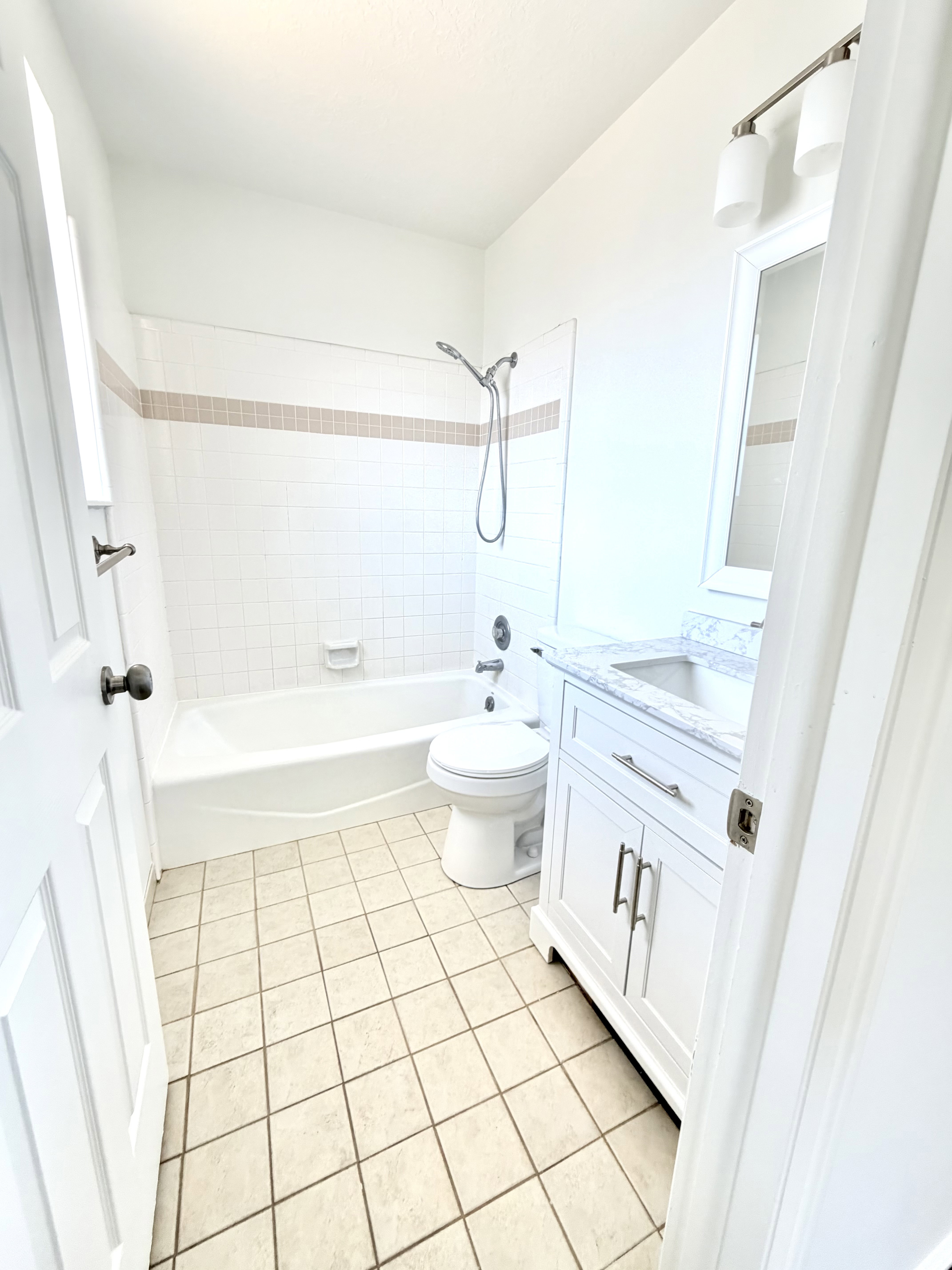 Bathroom featuring a white vanity with a light-colored countertop, a chrome faucet, and a large mirror with a white frame