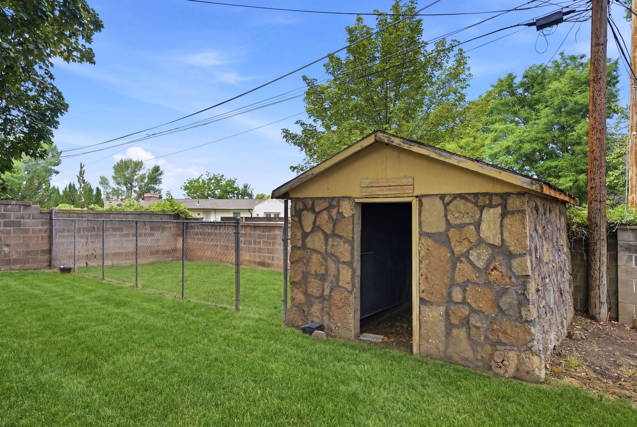 Stone-clad storage shed featuring an open doorway and gabled roofline