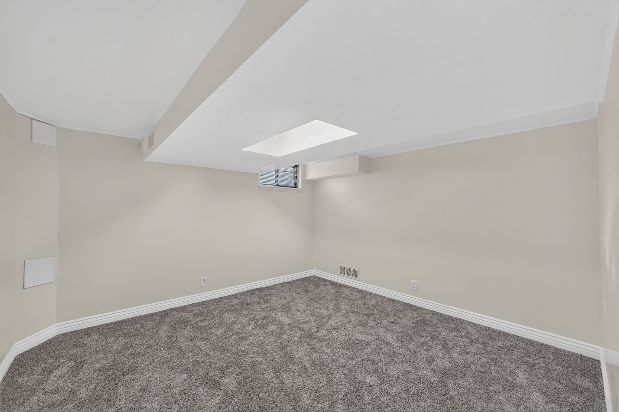 Carpeted room featuring light gray walls, white baseboards, and a recessed ceiling light fixture