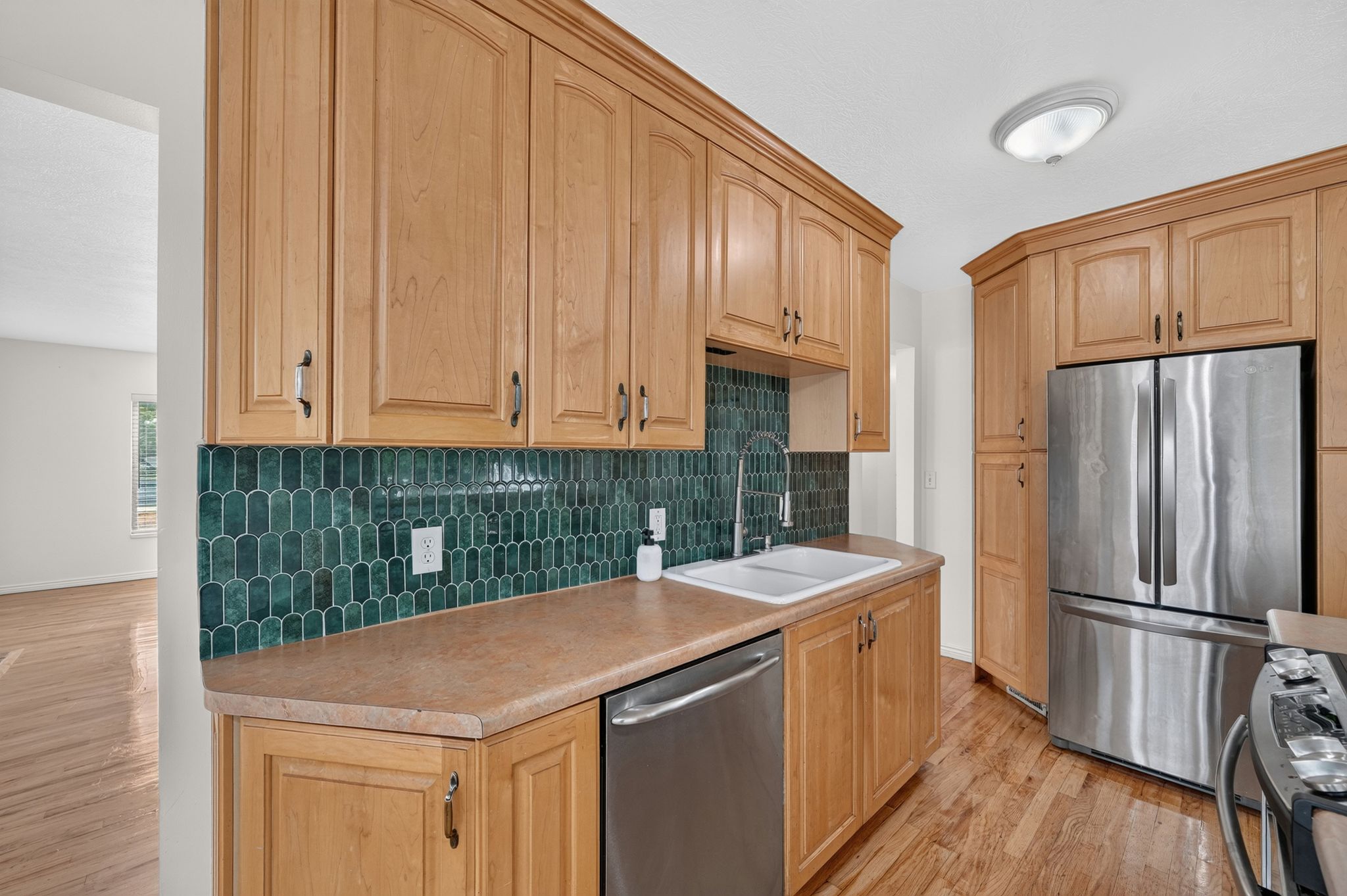 Kitchen featuring light wood cabinetry and a vibrant green picket tile backsplash