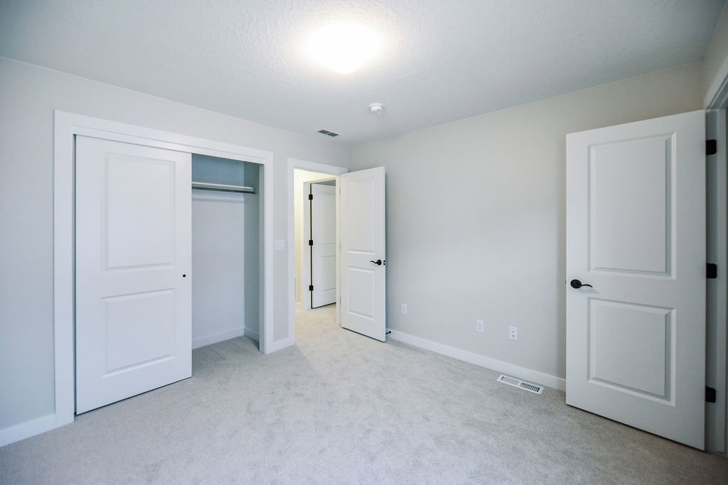 Carpeted room with a sliding closet featuring a hanging rod