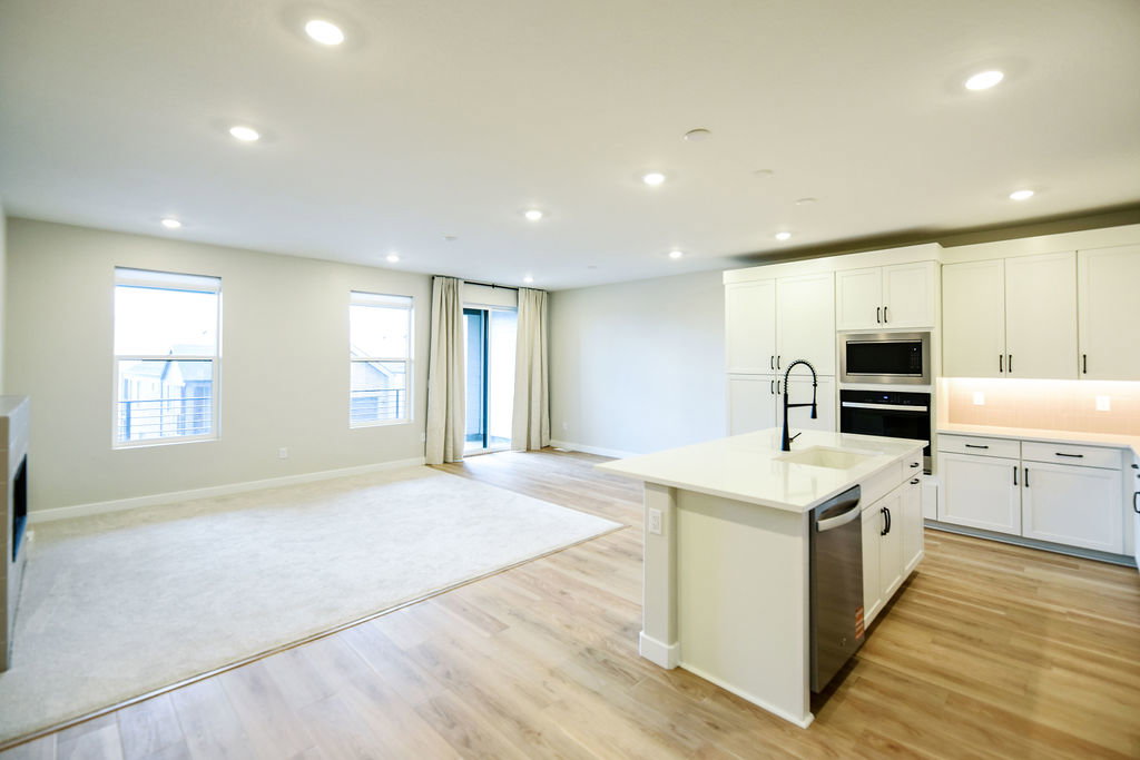 Open-concept living space featuring wood-finish flooring, recessed lighting, and a modern kitchen island with an integrated sink and dishwasher