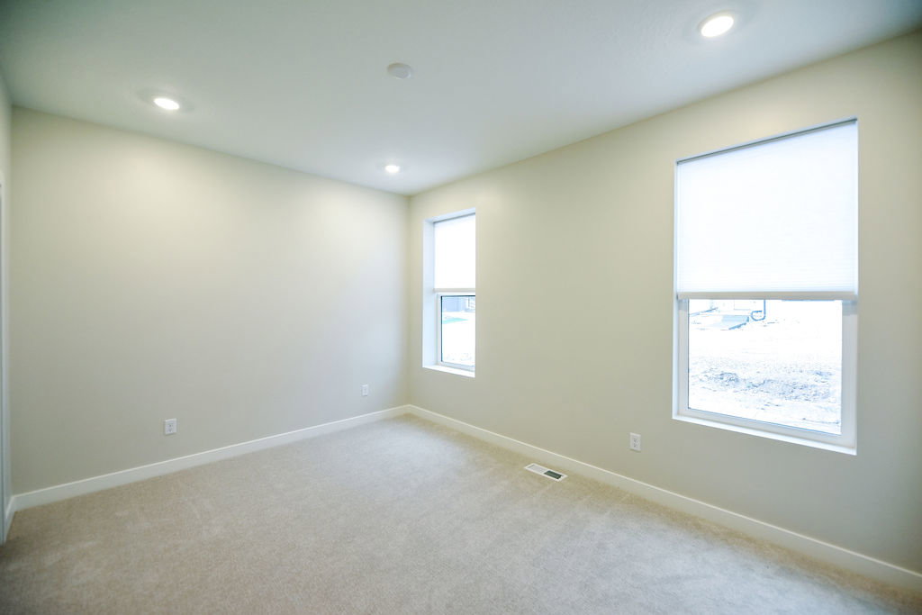 Carpeted room featuring recessed lighting, two windows with roller shades, and light-toned walls with white trim