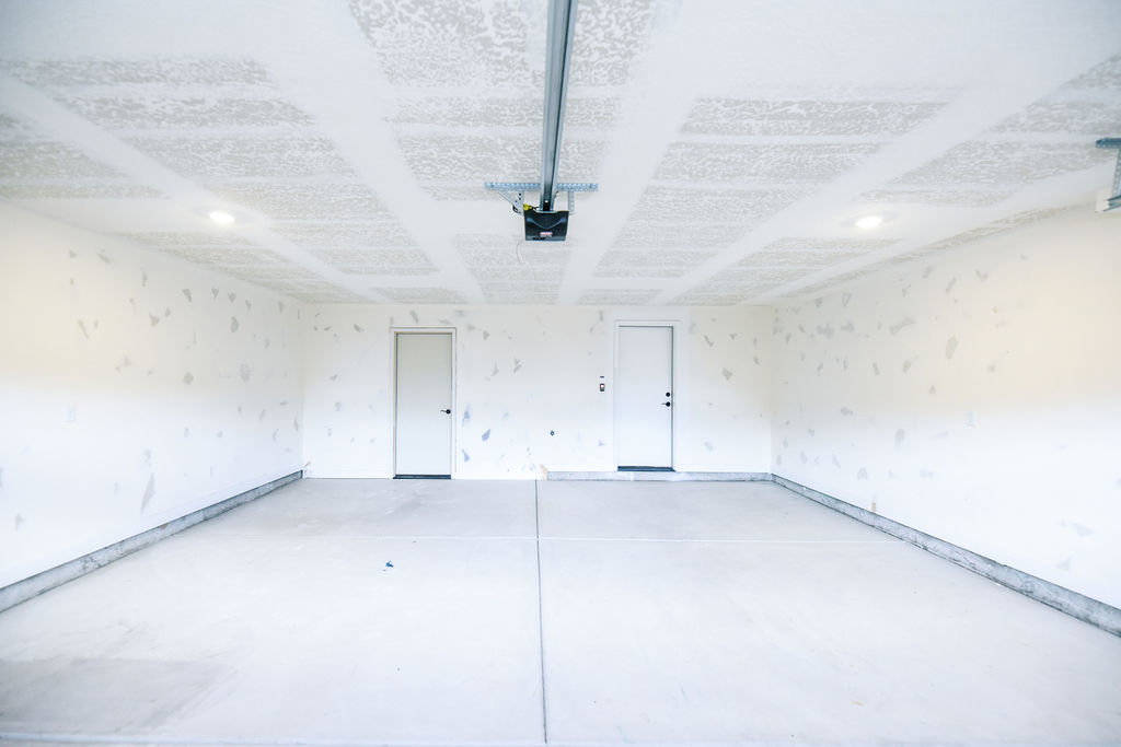 Spacious garage with concrete flooring, two access doors, and recessed lighting