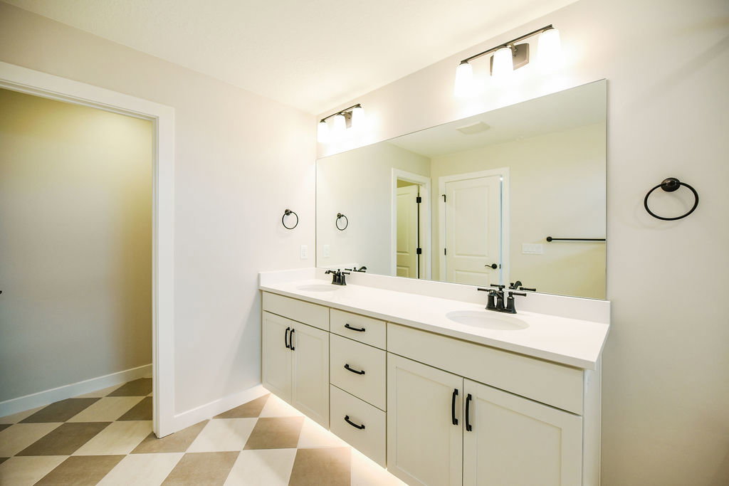 Dual vanity with white cabinetry, matte black hardware, and light-toned countertops