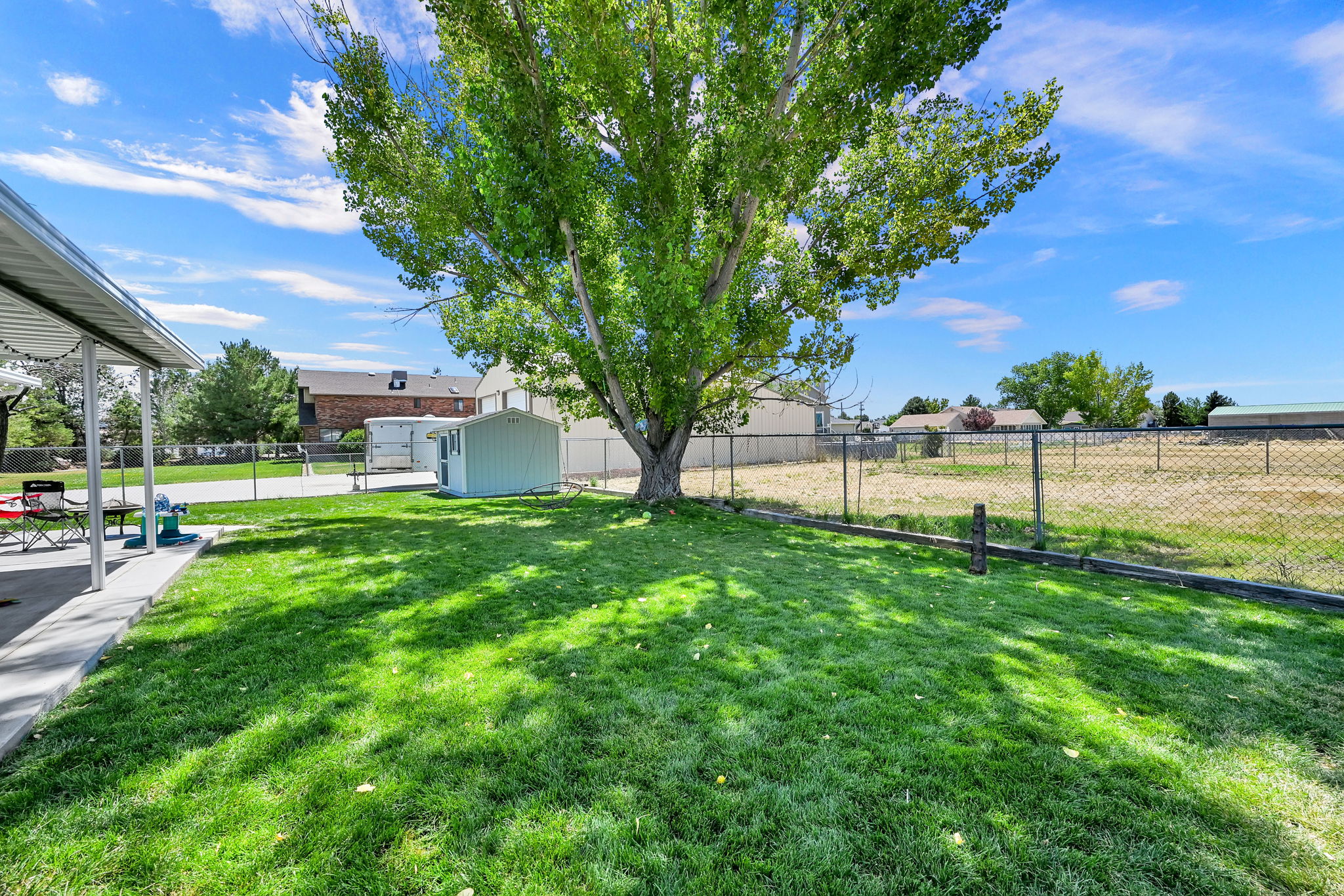 Expansive green lawn featuring a large mature tree providing natural shade