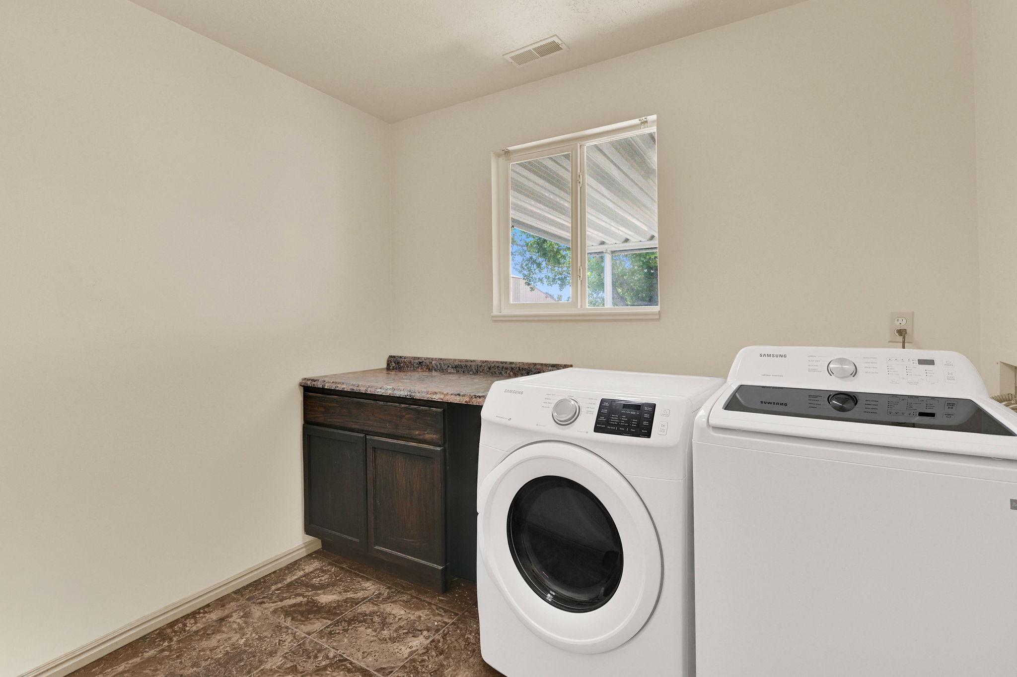 Laundry area featuring a window, built-in cabinetry with a countertop, and durable flooring
