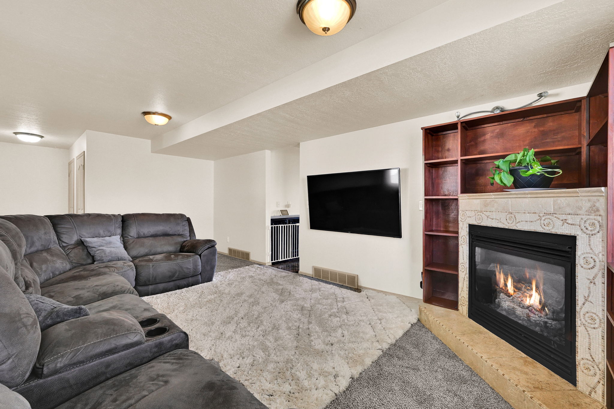 Living space featuring built-in shelving, a gas fireplace with a tiled surround, and recessed and flush-mount lighting fixtures