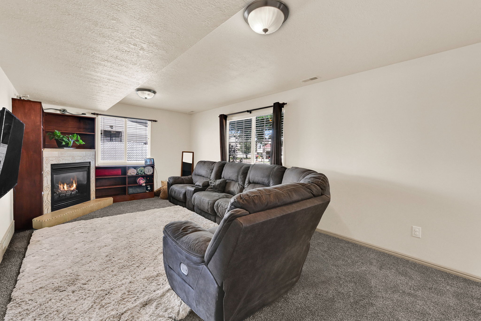 Living area featuring a built-in fireplace with a stone surround, integrated shelving, and dark-toned carpeting