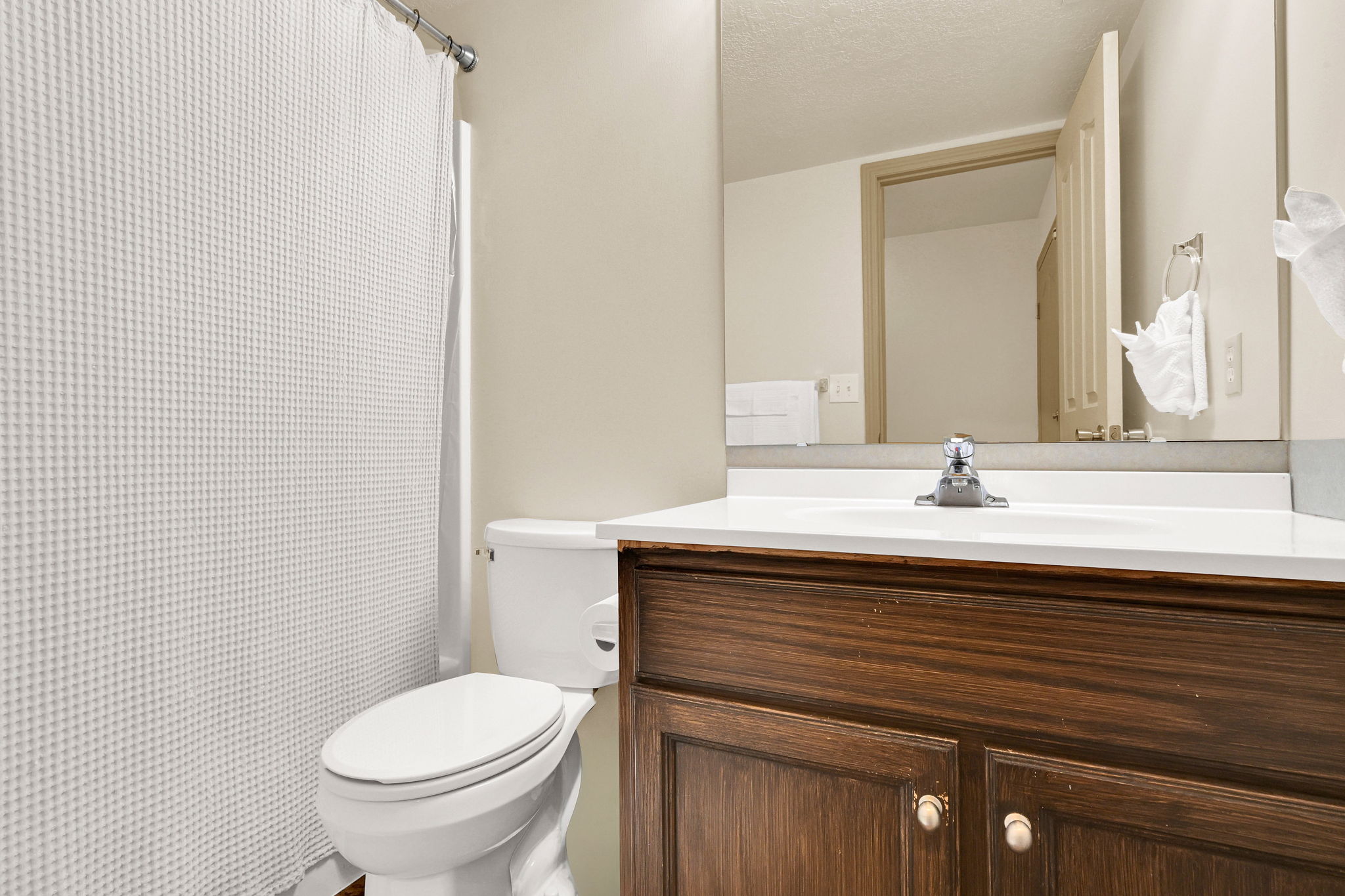 Bathroom featuring a white toilet, dark wood-finish vanity with a white countertop, and a chrome faucet
