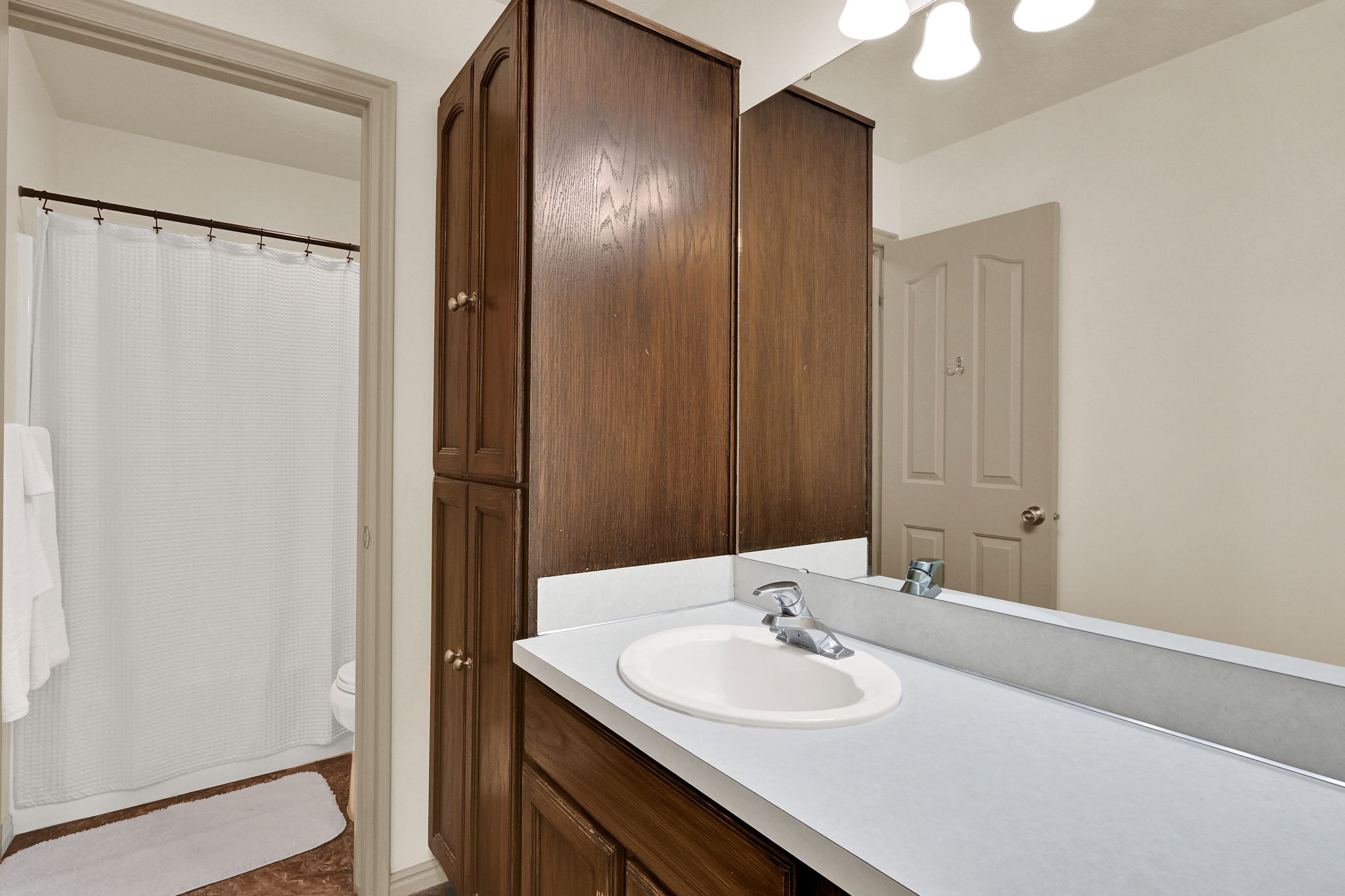 Bathroom vanity with an integrated sink, laminate countertop, and wood cabinetry
