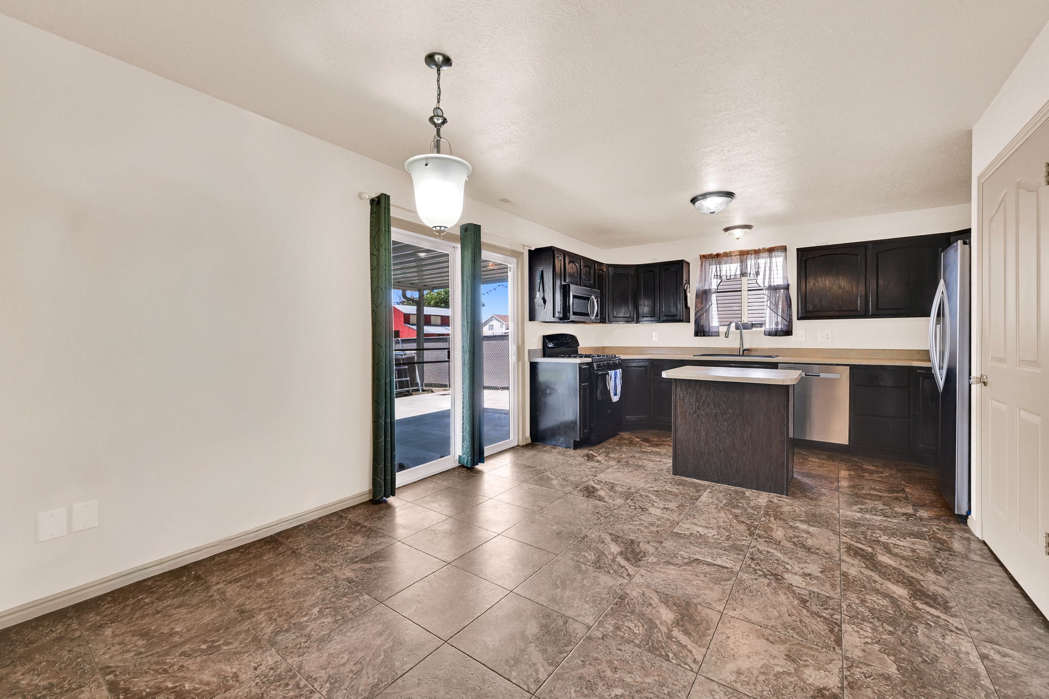 Spacious kitchen and dining area with dark wood-finish cabinetry, light-toned countertops, and an integrated kitchen island