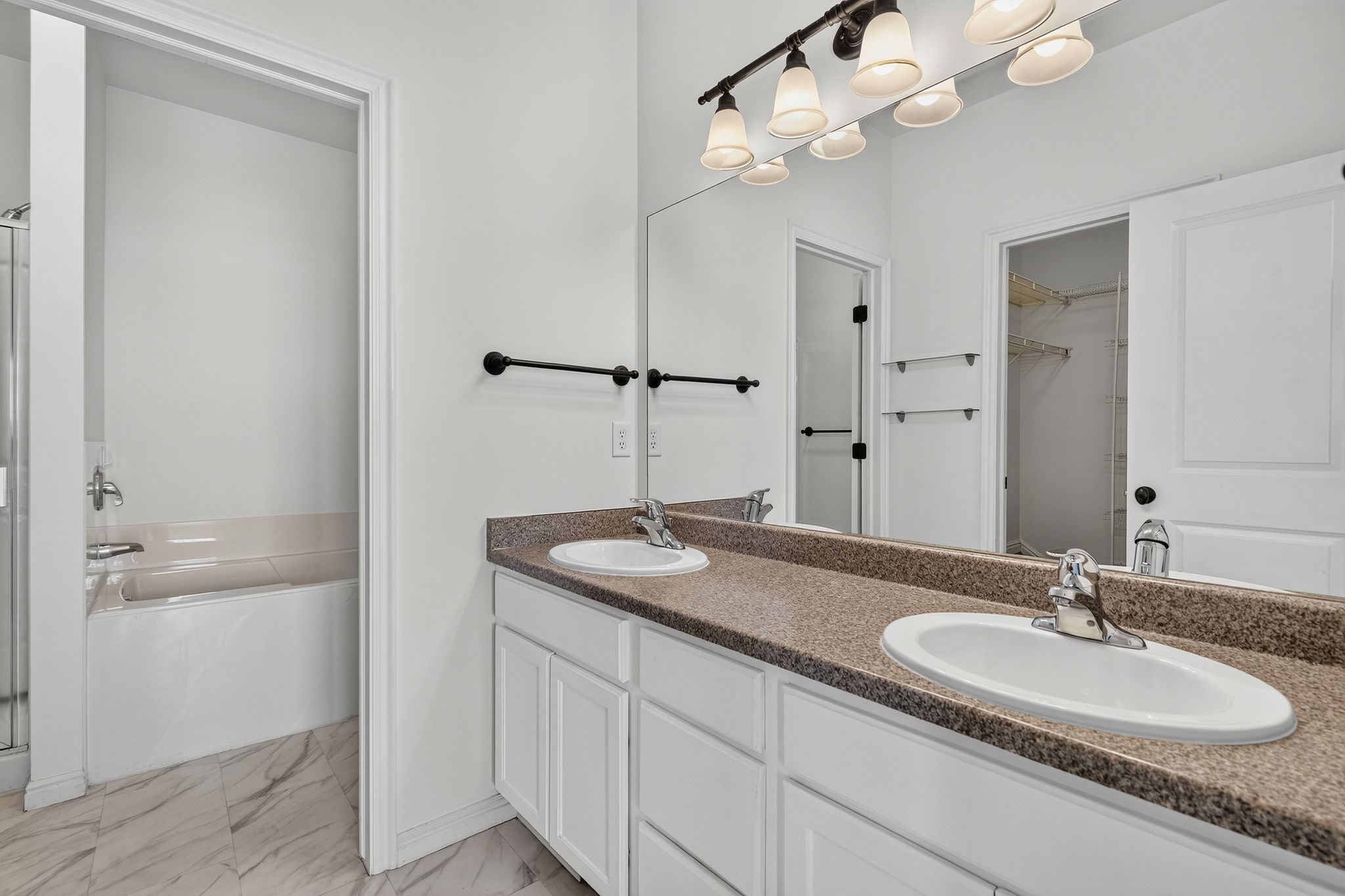 Dual vanity featuring white cabinetry, a speckled countertop, and chrome fixtures