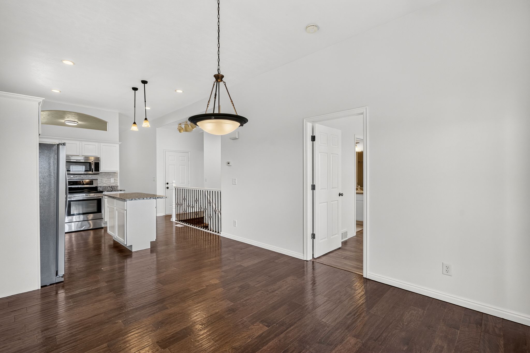 Open-concept living area featuring rich wood-finish flooring, recessed lighting, and a kitchen with stainless steel appliances