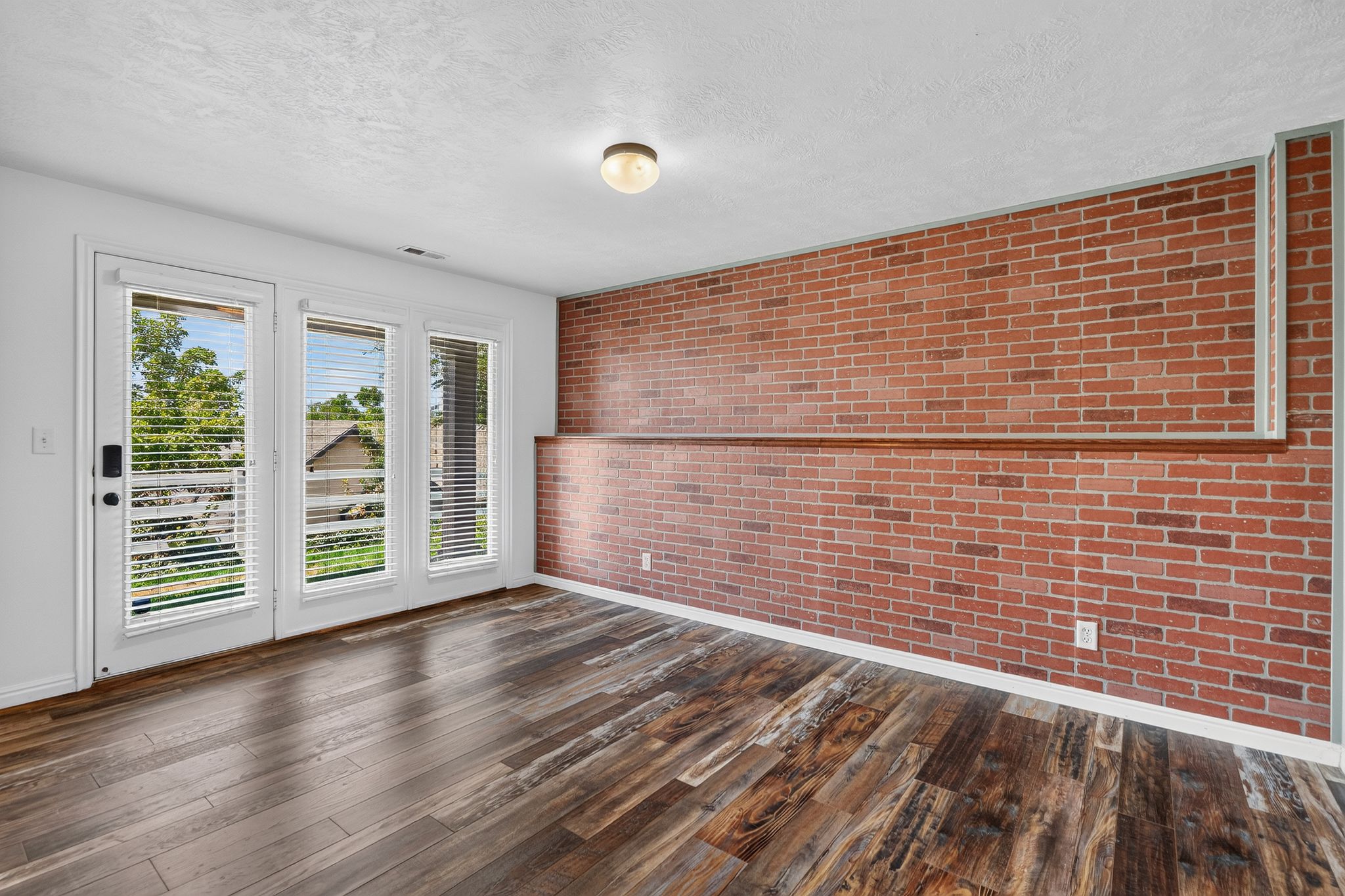 Wood-finish flooring throughout, complemented by a brick accent wall with a wood ledge