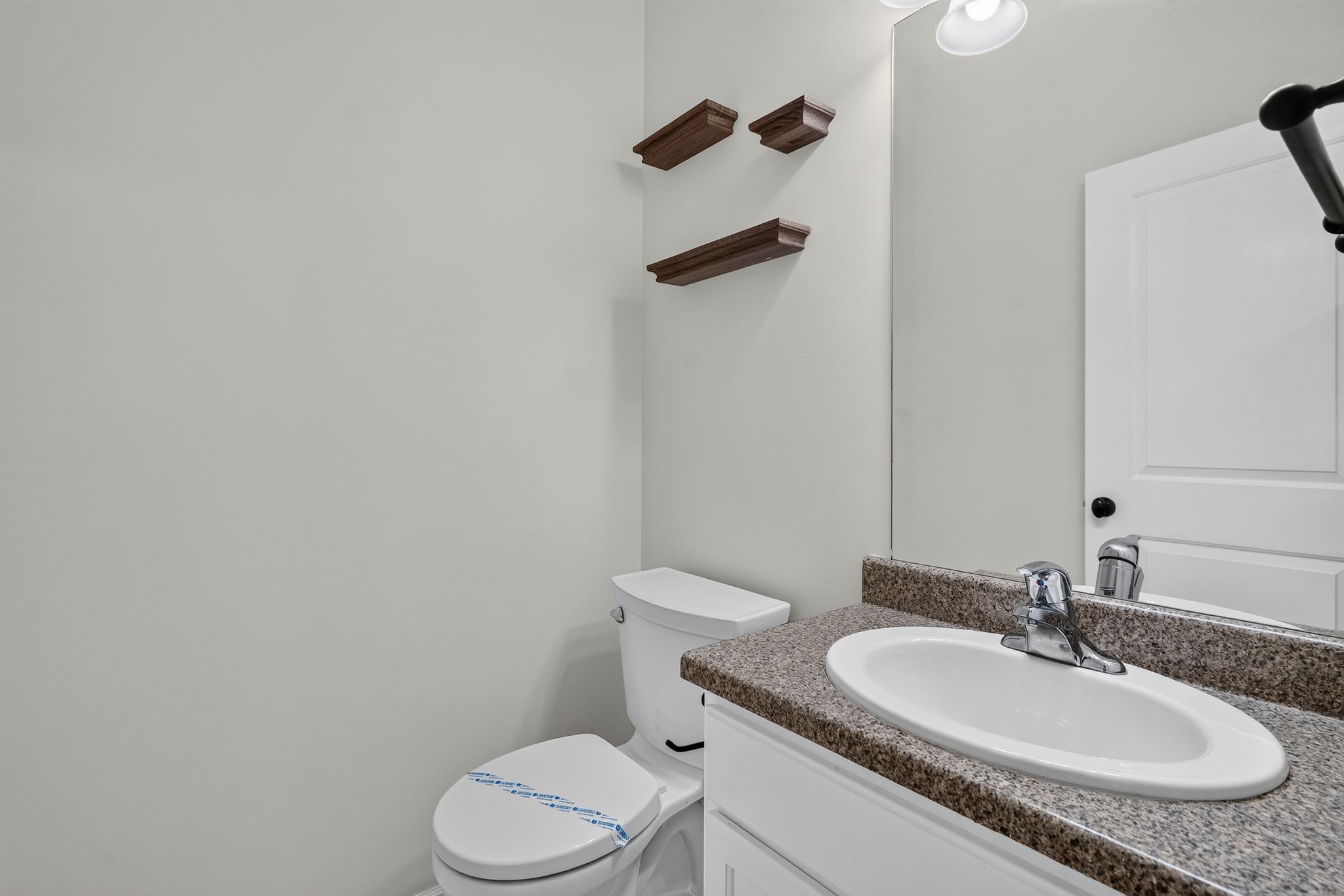 Bathroom featuring a vanity with a speckled countertop, an undermount sink, and a chrome faucet