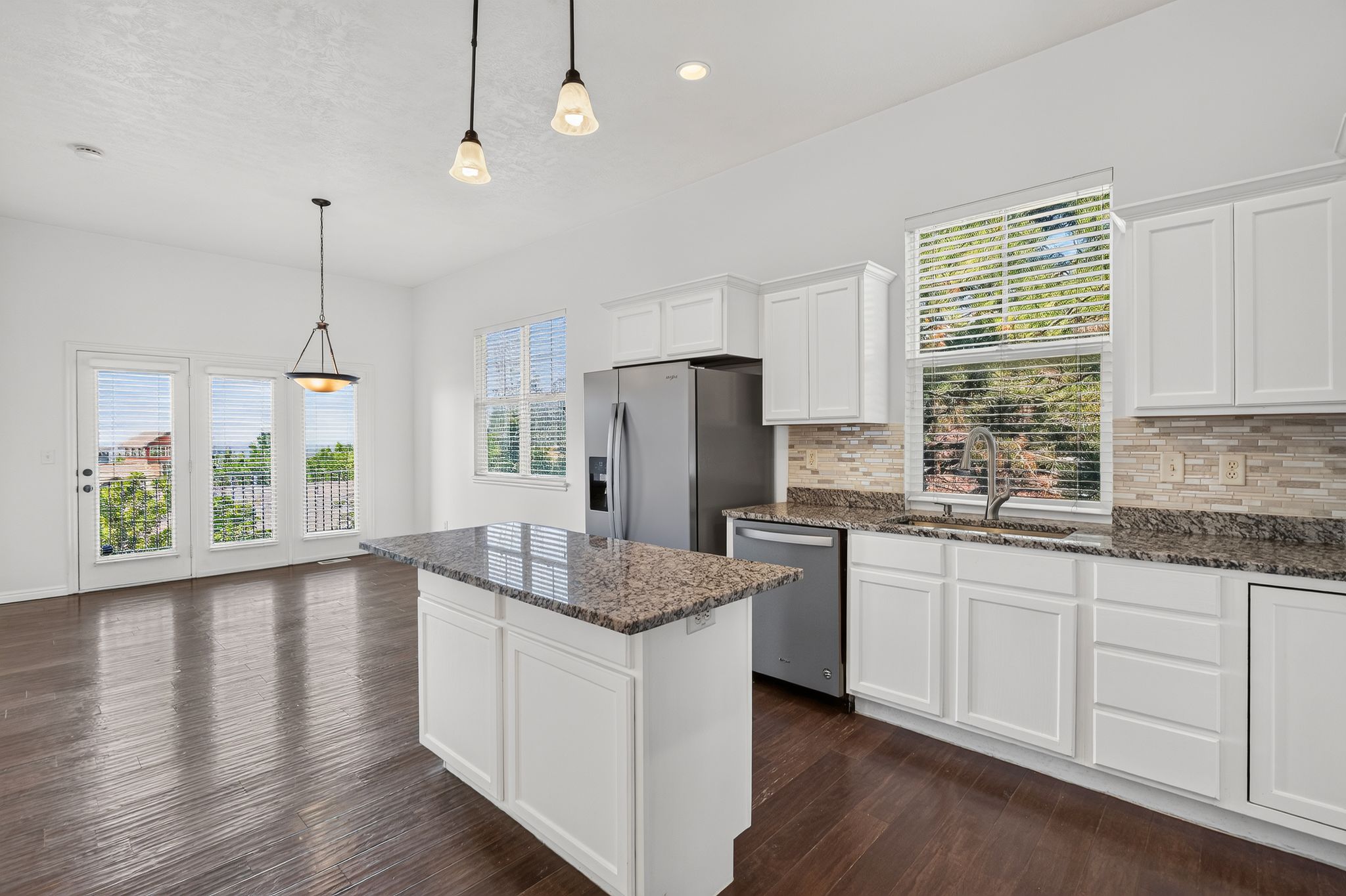 Kitchen featuring white shaker cabinetry, stainless steel appliances, granite countertops, and a tile backsplash
