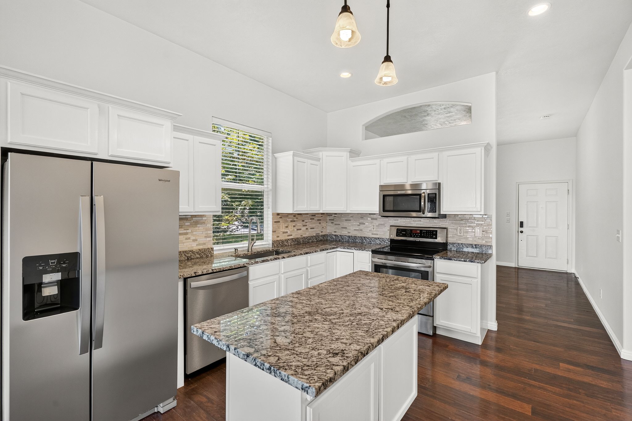 Modern kitchen featuring white cabinetry, stainless steel appliances, and wood-finish flooring