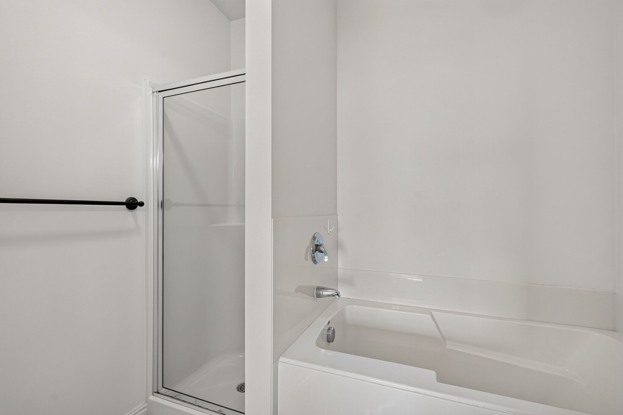 Bathroom featuring a white bathtub, chrome fixtures, and an enclosed shower with a glass door