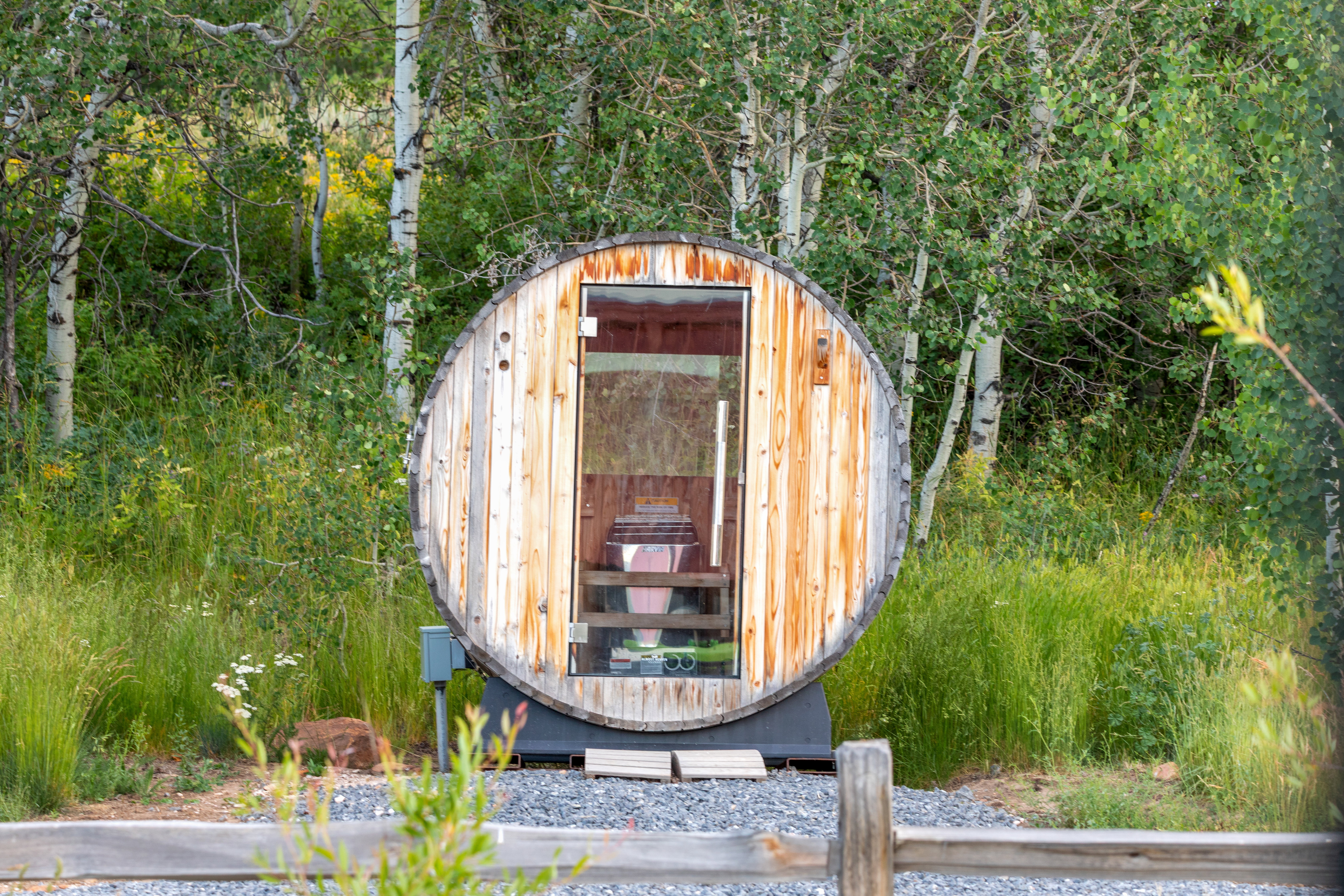 Barrel-style outdoor sauna with a clear glass door